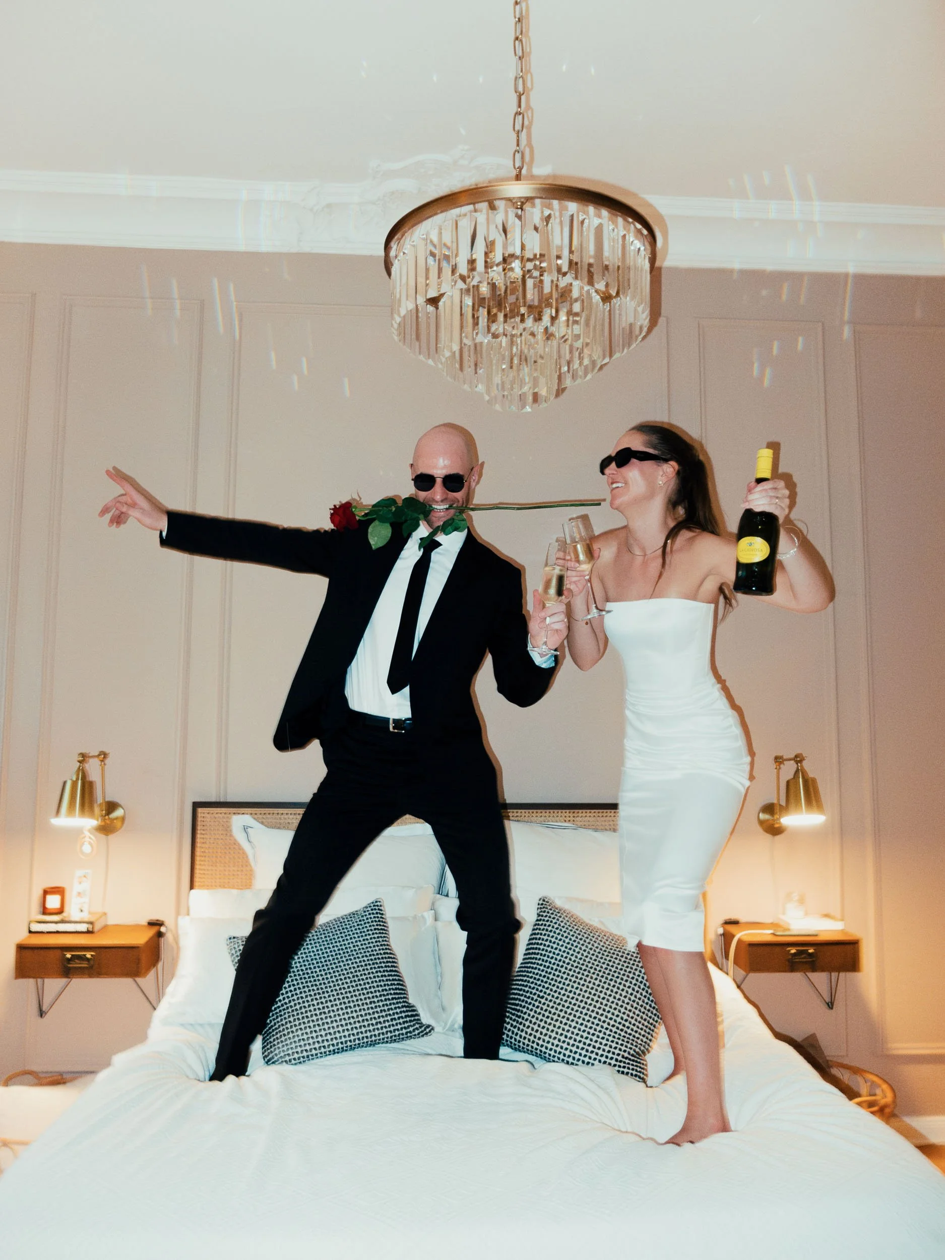 Fun, unposed wedding couple jumping on bed – modern and playful documentary moment captured by Studio Aelina