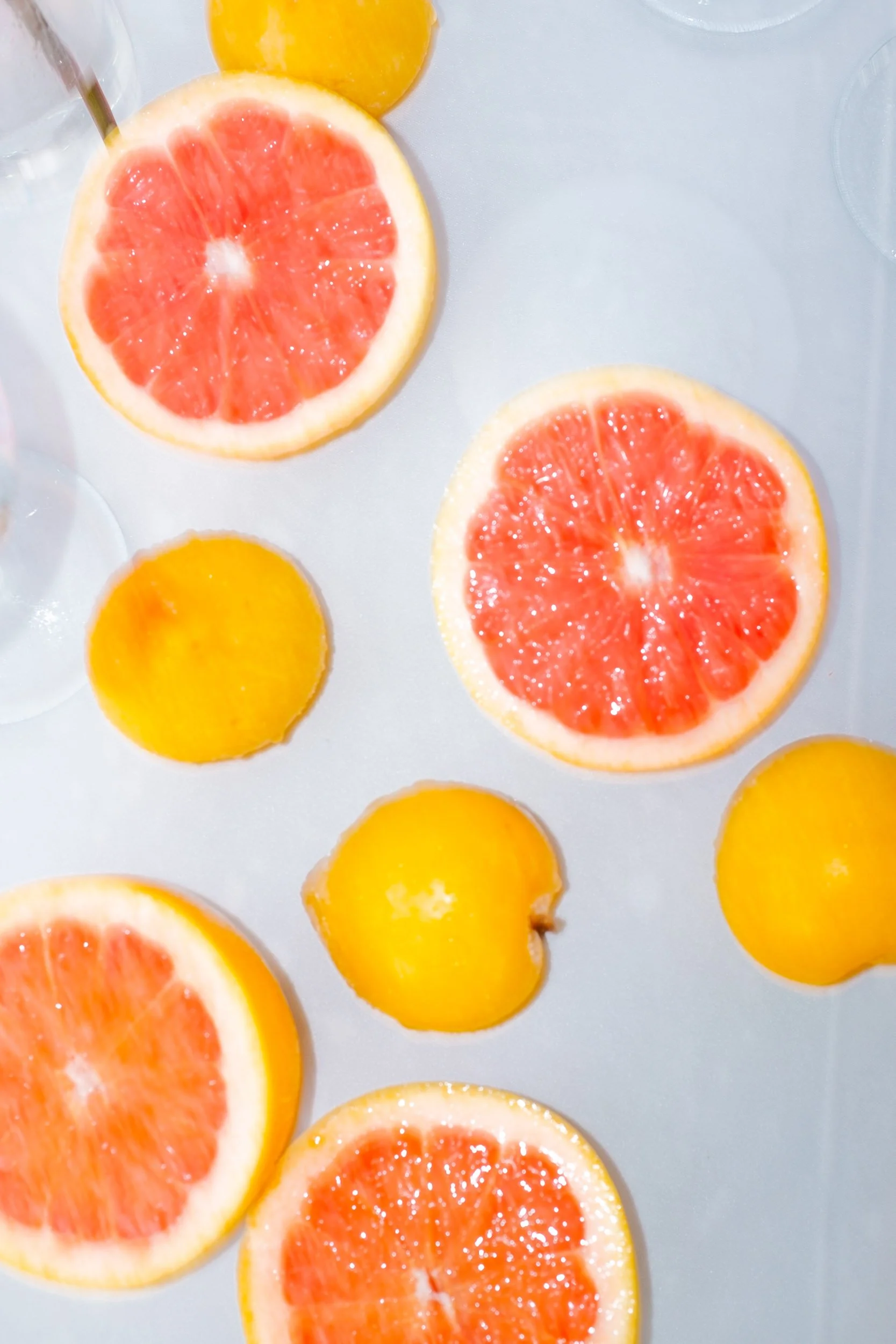 Slices of grapefruit and whole lemons on a white surface – vibrant wedding photography in Mallorca by Studio Aelina