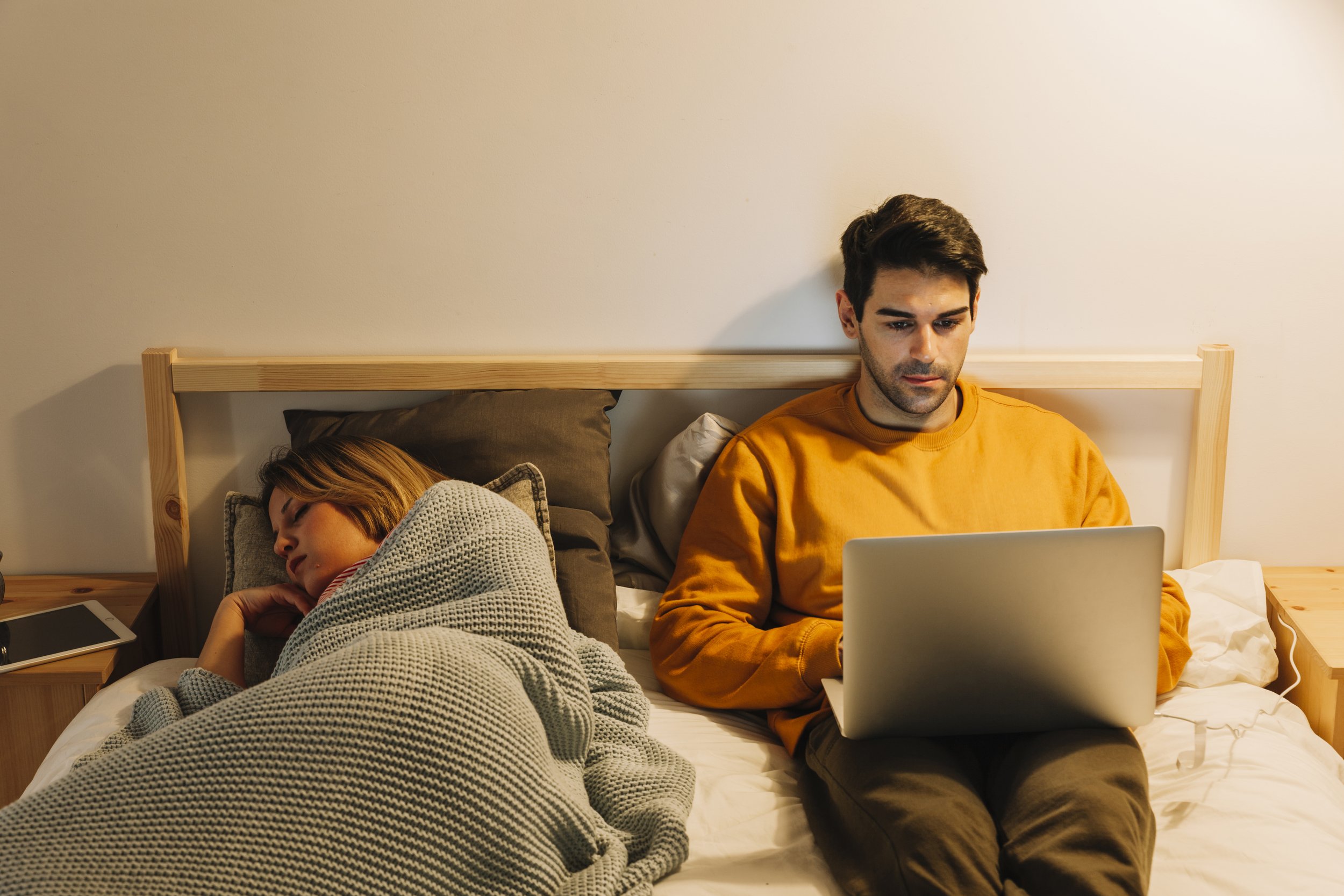 Man researching vehicles in bed whilst his partner sleeps