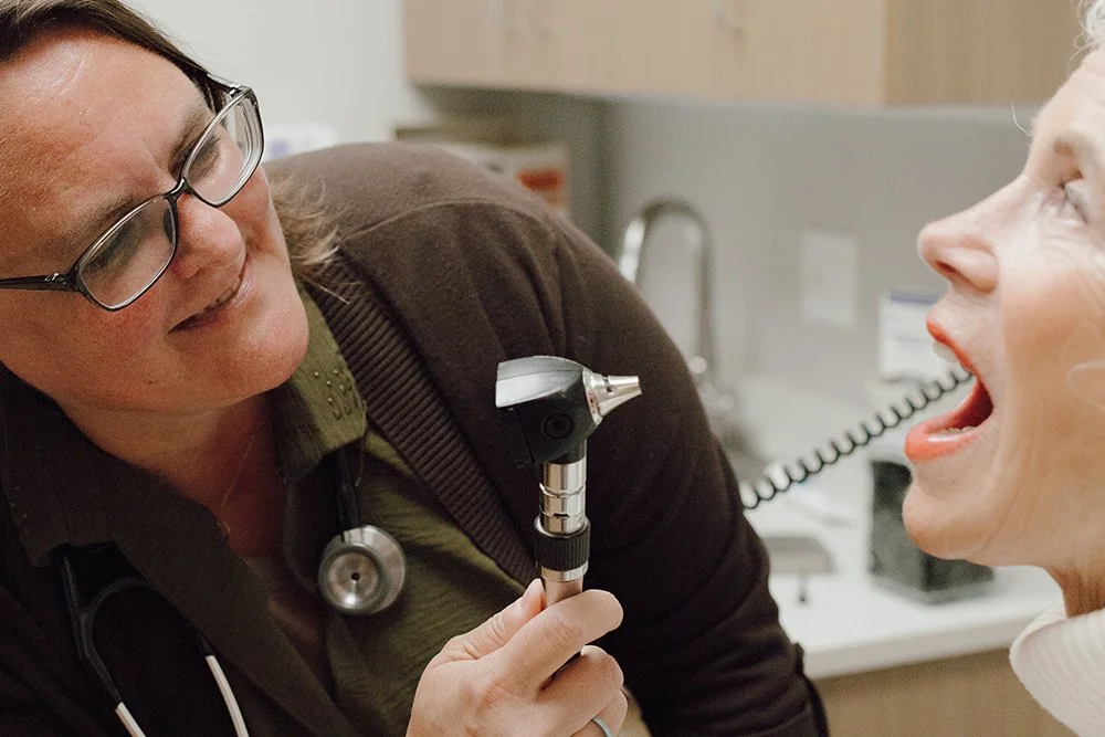 A healthcare professional examines a patient's throat with an otoscope.