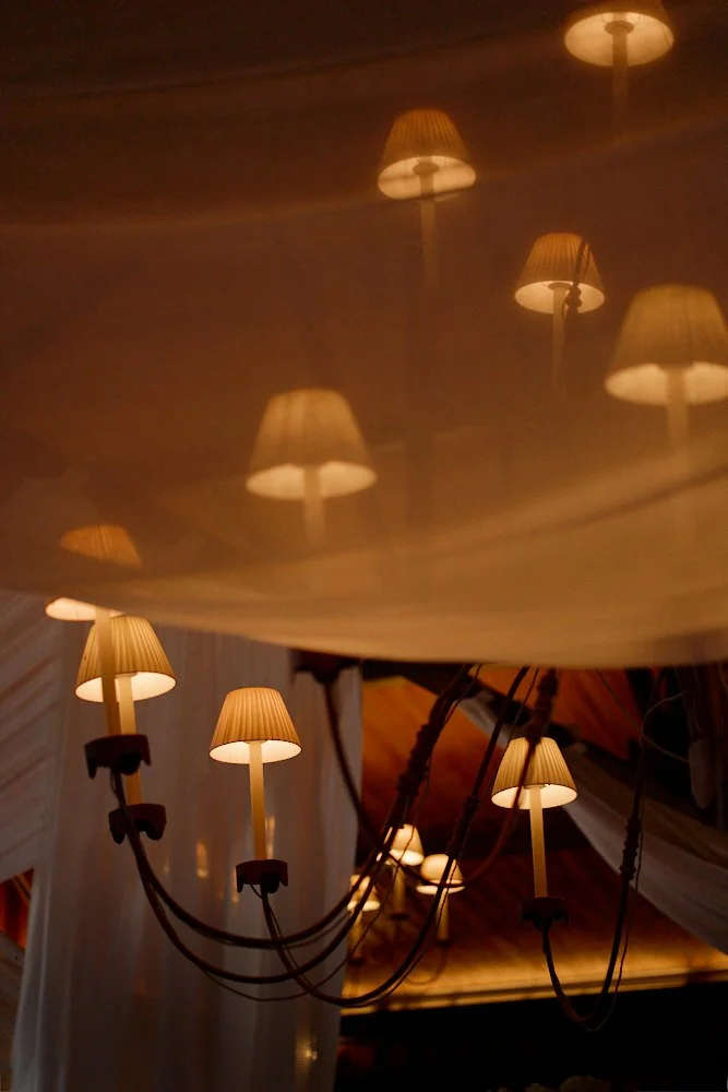 Multiple wall-mounted lamps with beige shades reflecting on a glossy, mirrored ceiling.