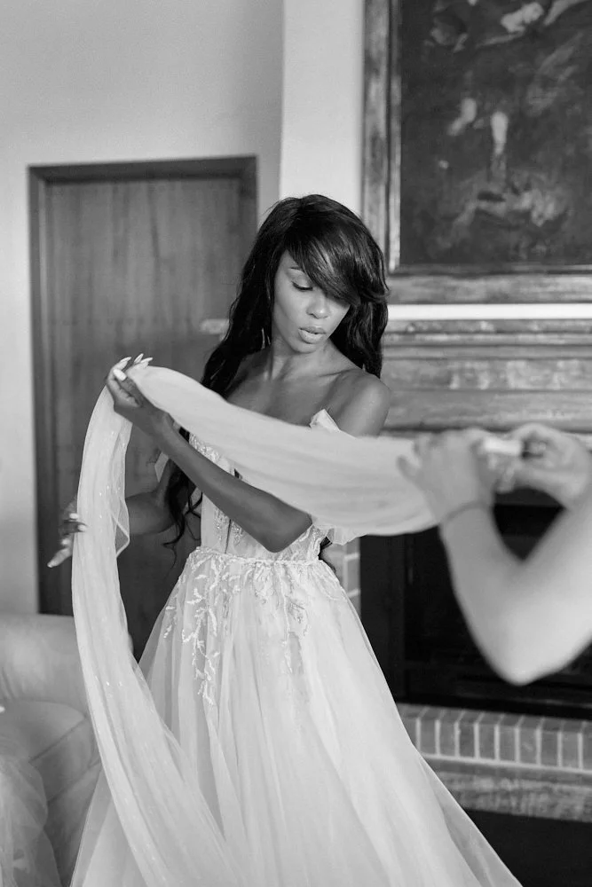 A woman in a wedding dress holding a long, flowing fabric in a living room.