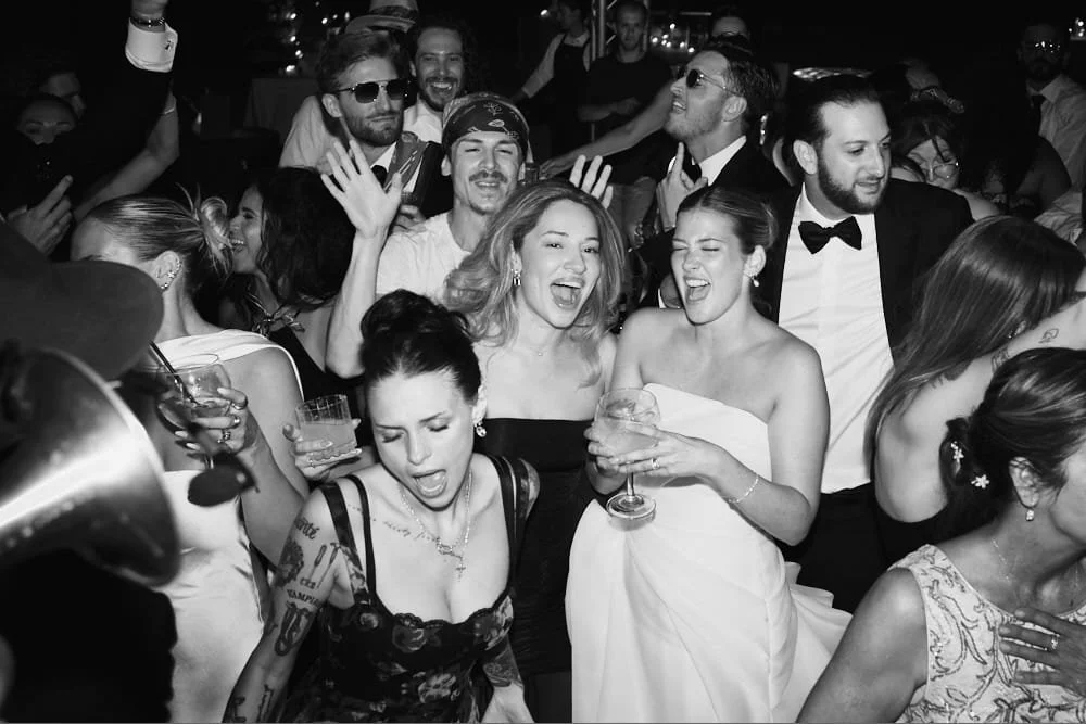 People partying at a lively social event, some dancing and holding drinks