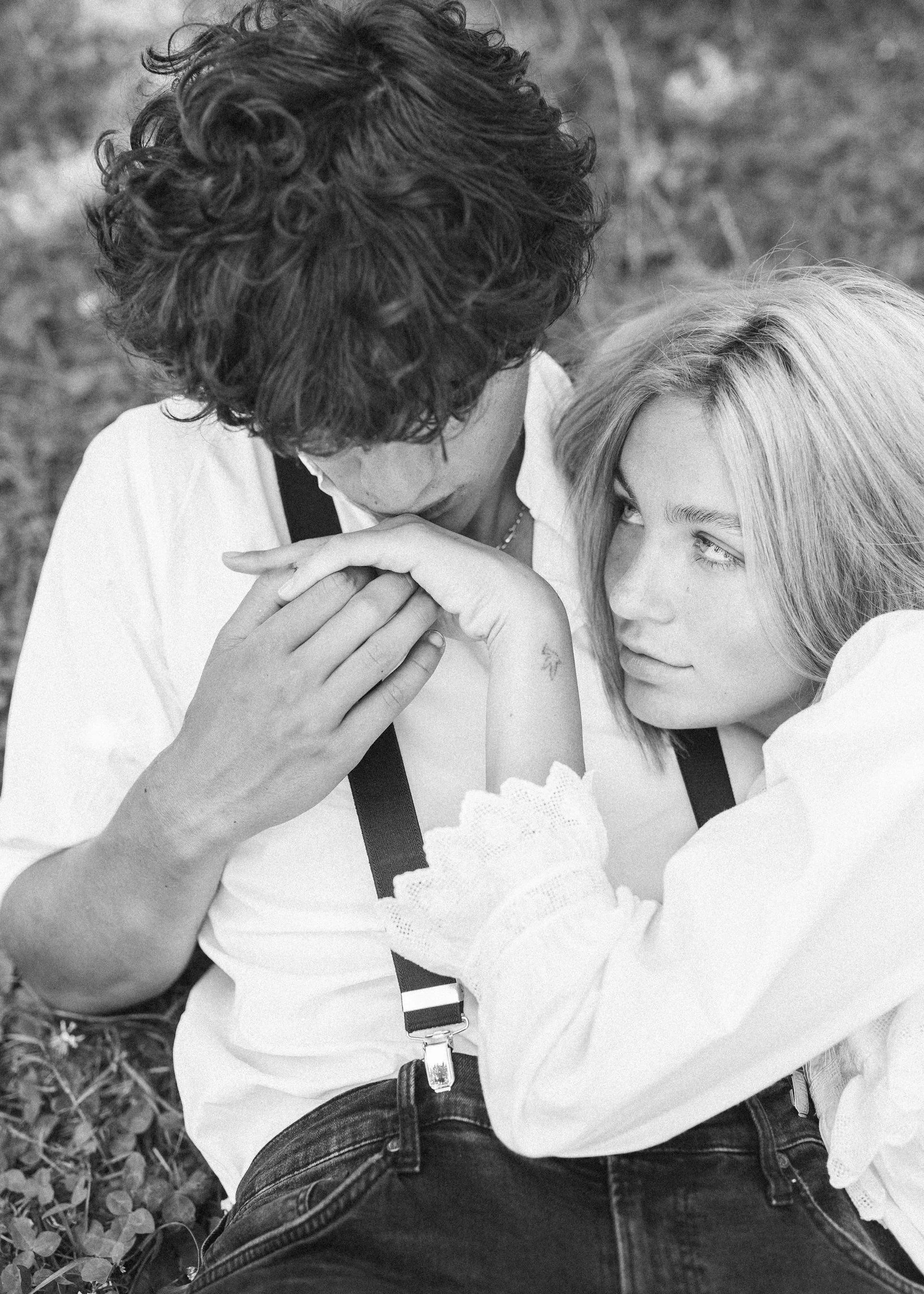 Wedding Website Design, Digital Wedding Stationery, Web Design and Branding for Wedding Professionals | Avelã White. Black and white photo of a couple sitting closely, with the man gently holding the woman’s hand and the woman looking at him.