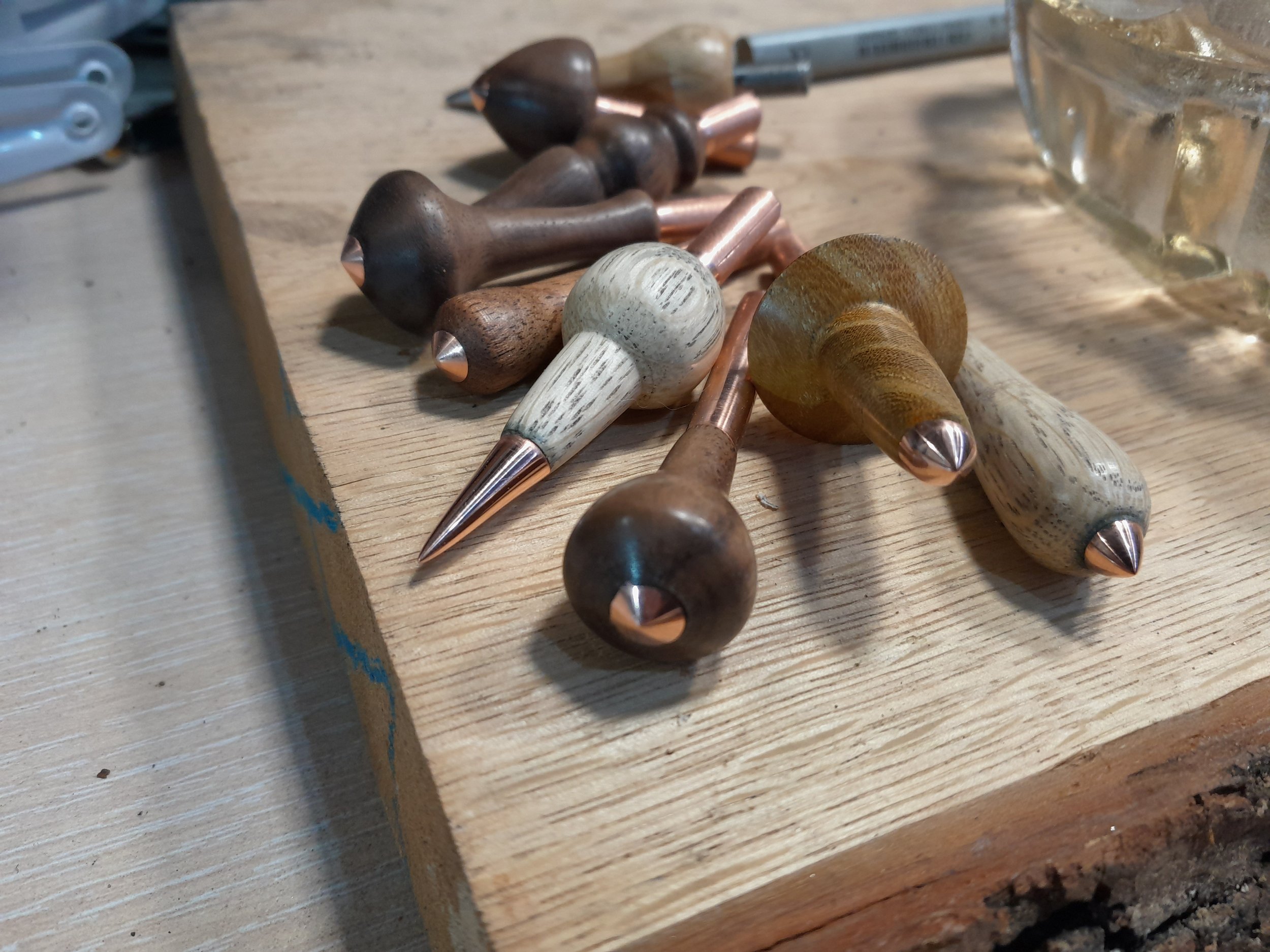 Wooden handles with copper tips on a wooden surface