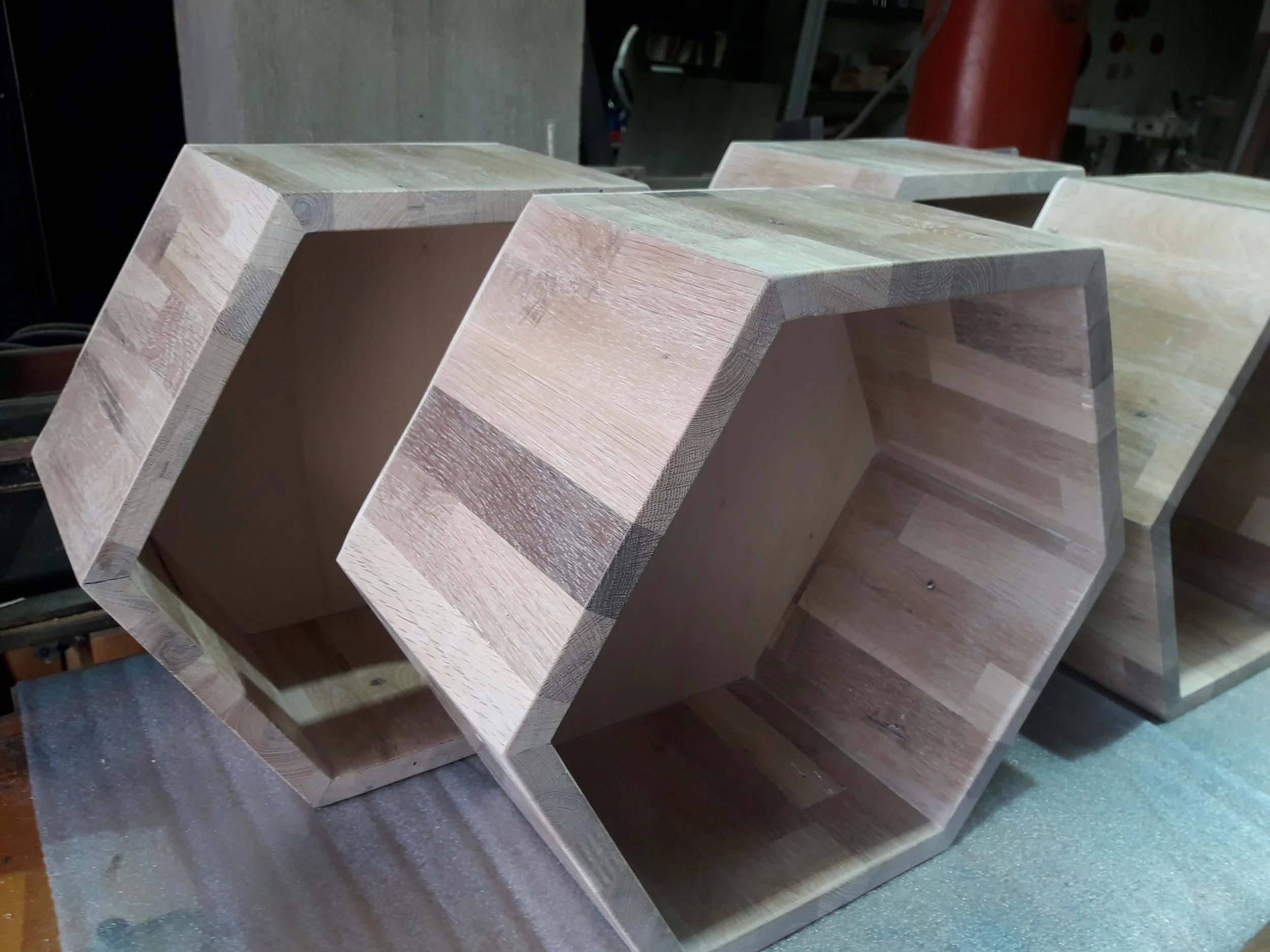 Wooden hexagonal shelves stacked on a workshop surface.