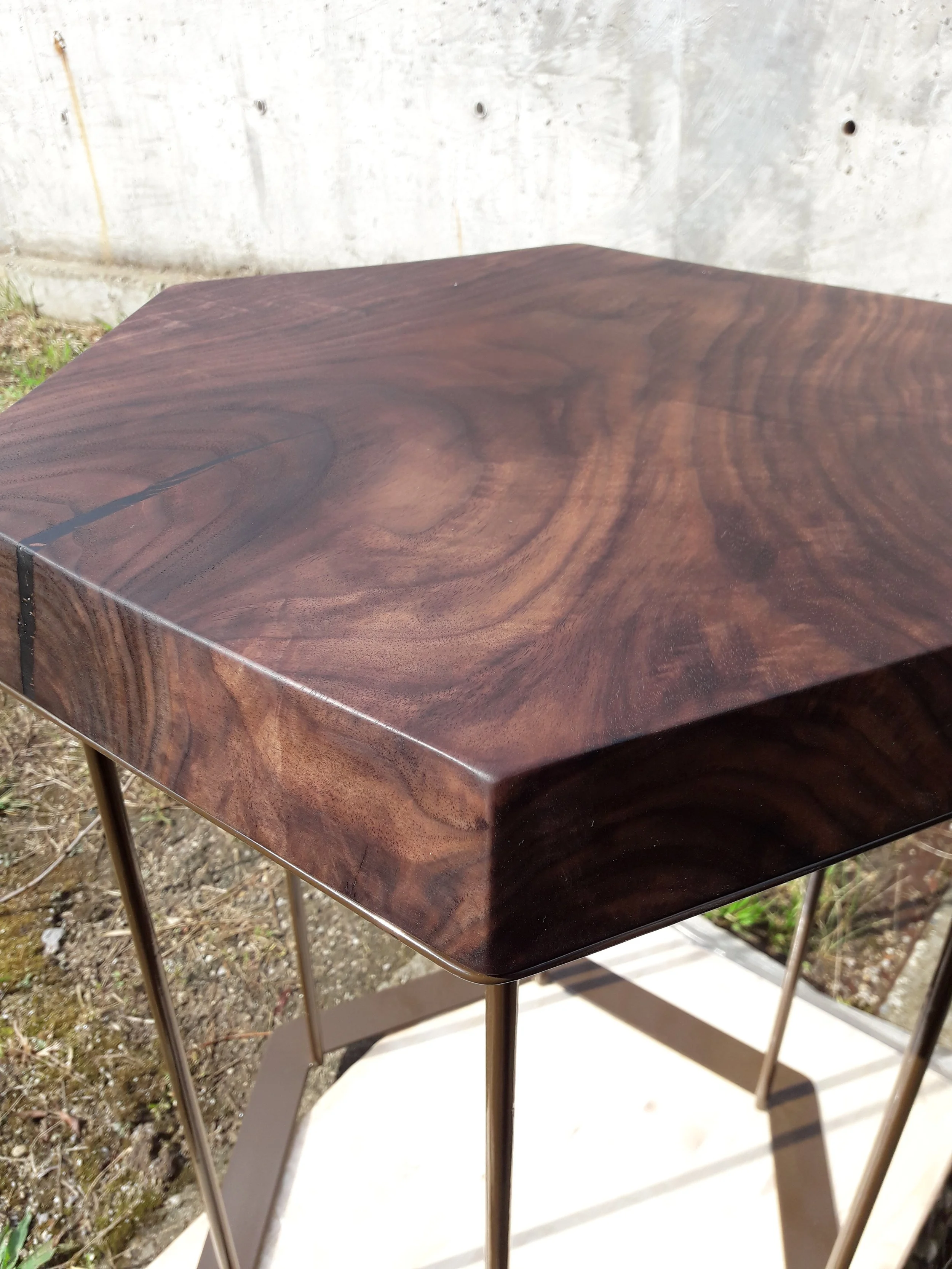 Hexagonal wooden table with a dark finish and metal legs.