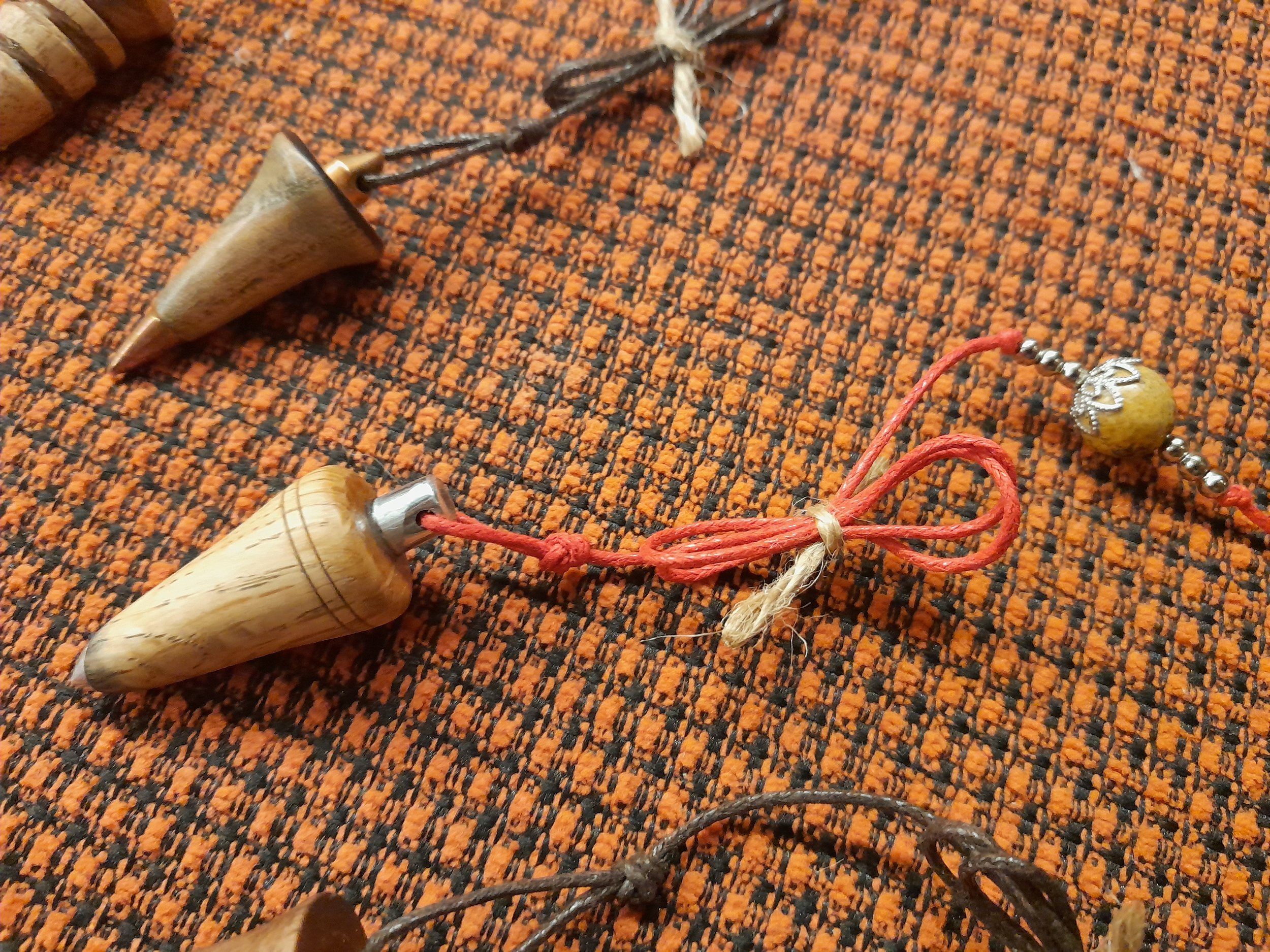 Wooden pendulums with string on an orange woven surface