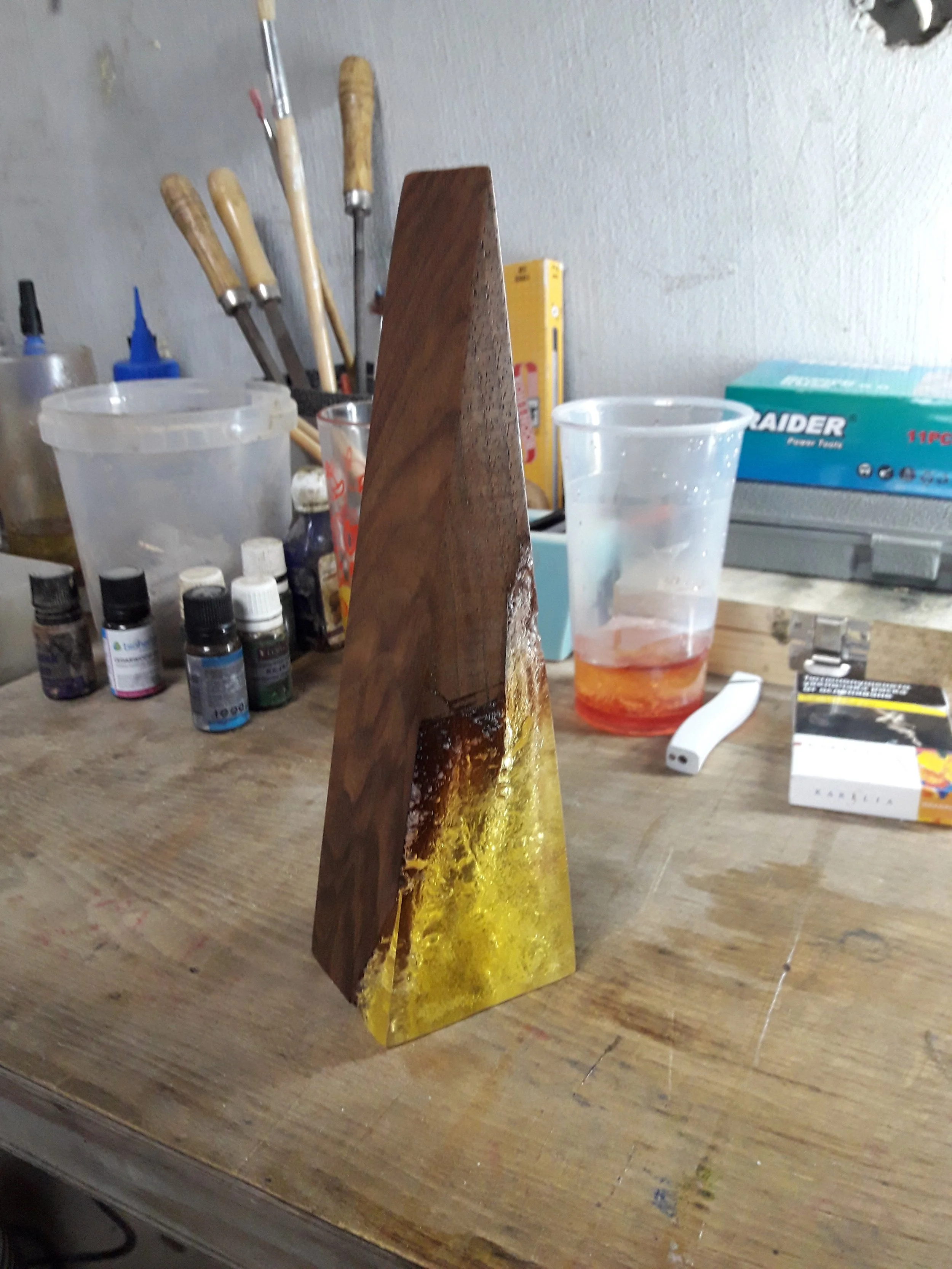 A wooden and resin decorative piece on a workbench with art supplies in the background.