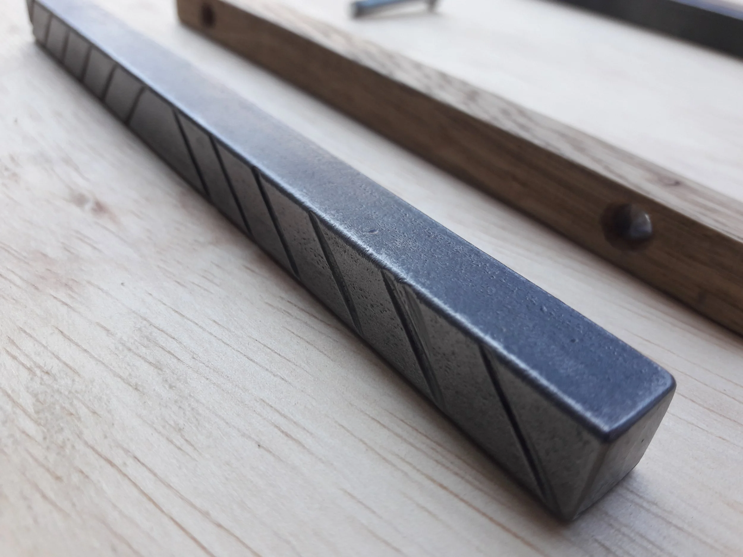 Close-up of a metal and a wooden bar on a light-colored surface