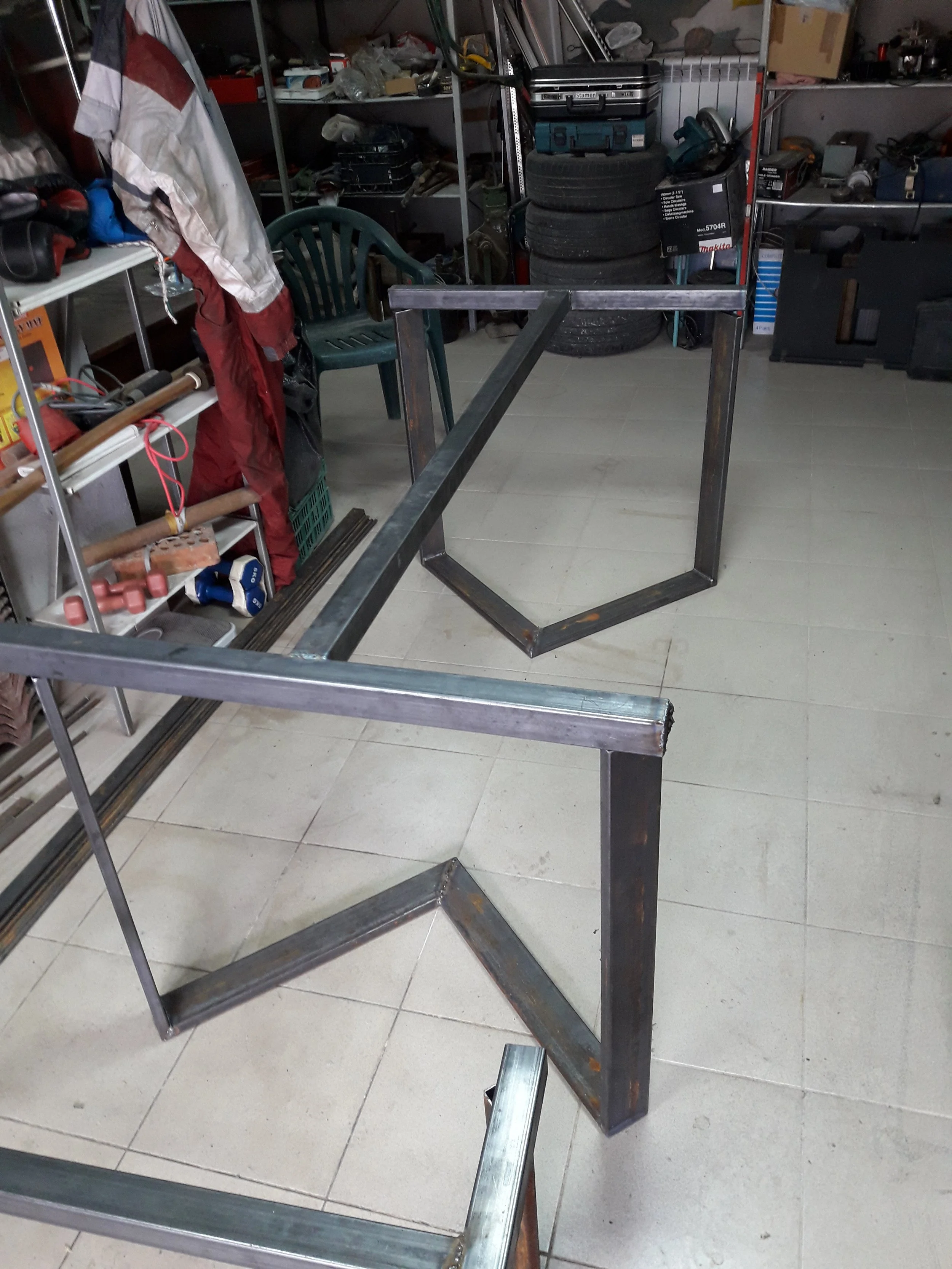 Metal table frame in workshop with tools and tires
