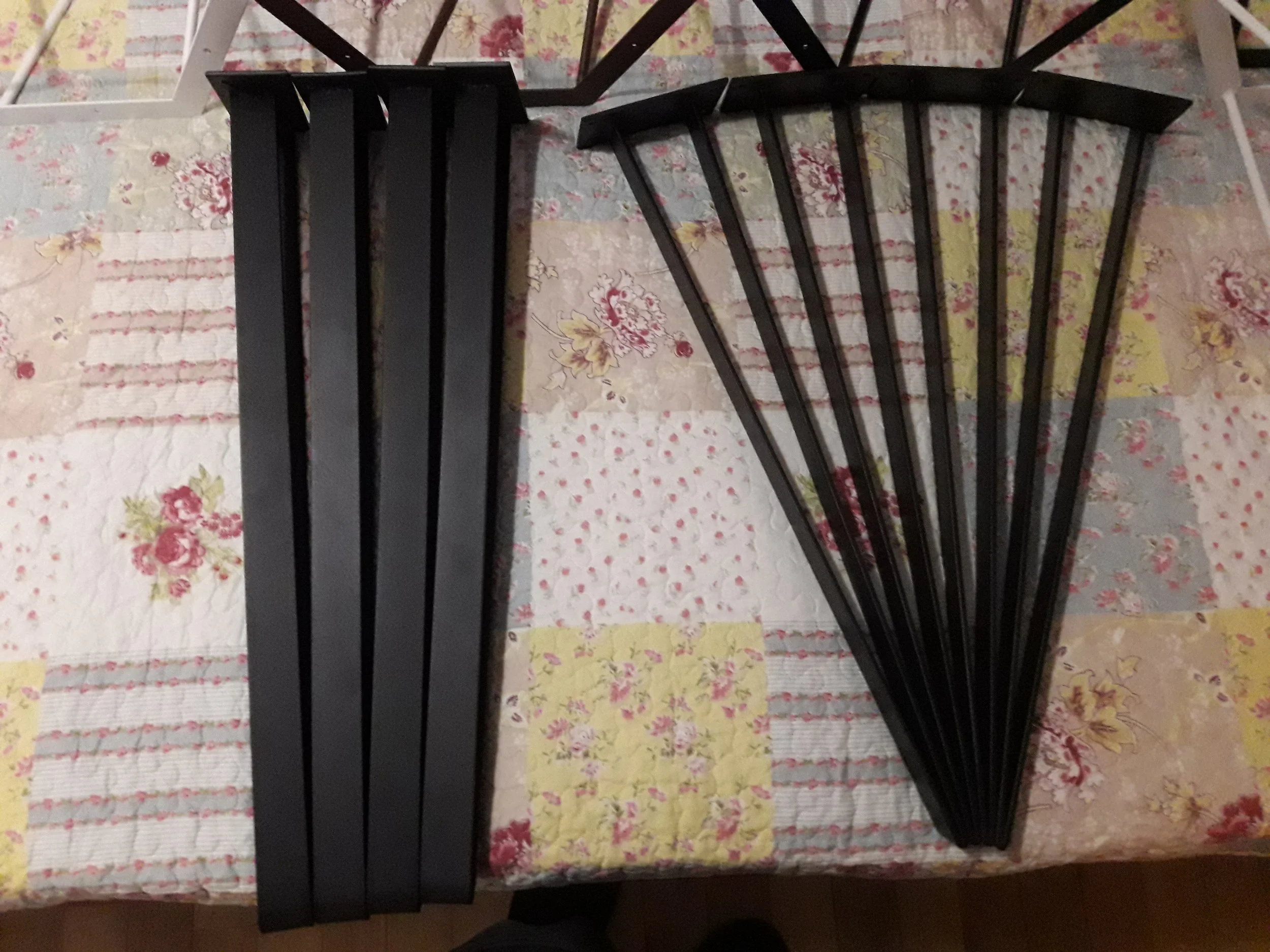 Black metal chair legs and backrest on a floral quilted bedspread