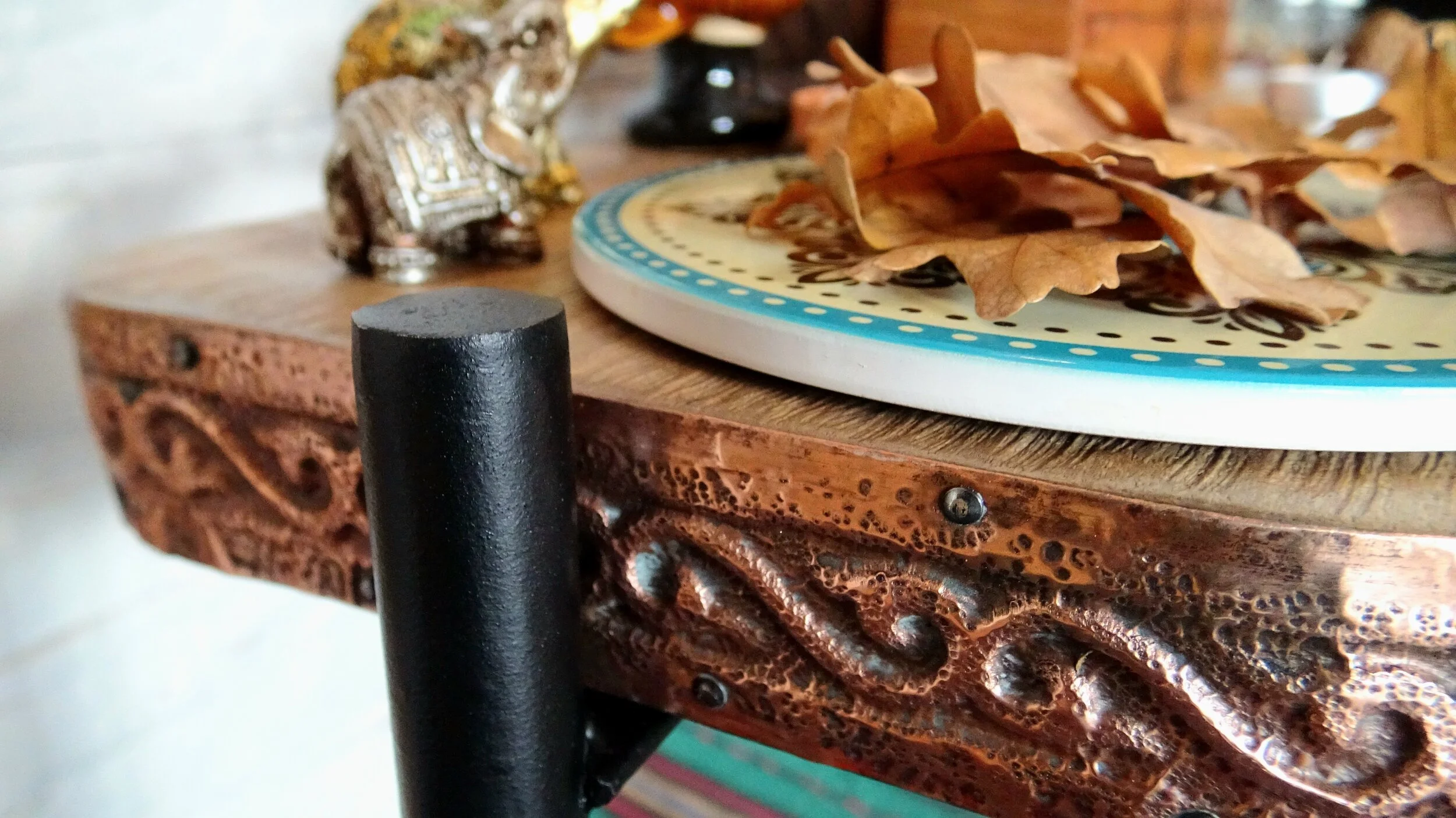 Decorative shelf with copper detailing, elephant figurine, and plate with dried leaves