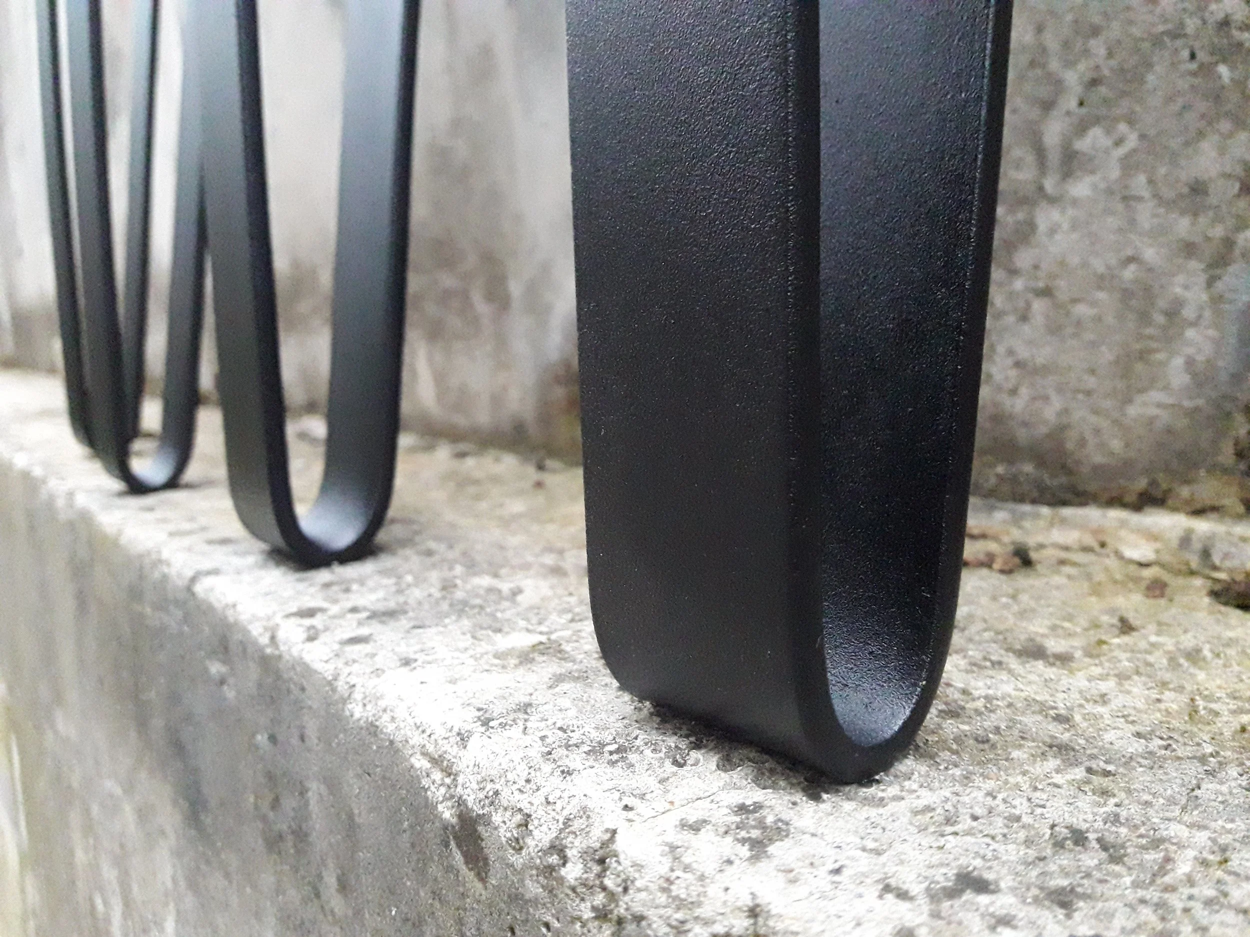 Close-up of metal hairpin legs on a concrete surface.