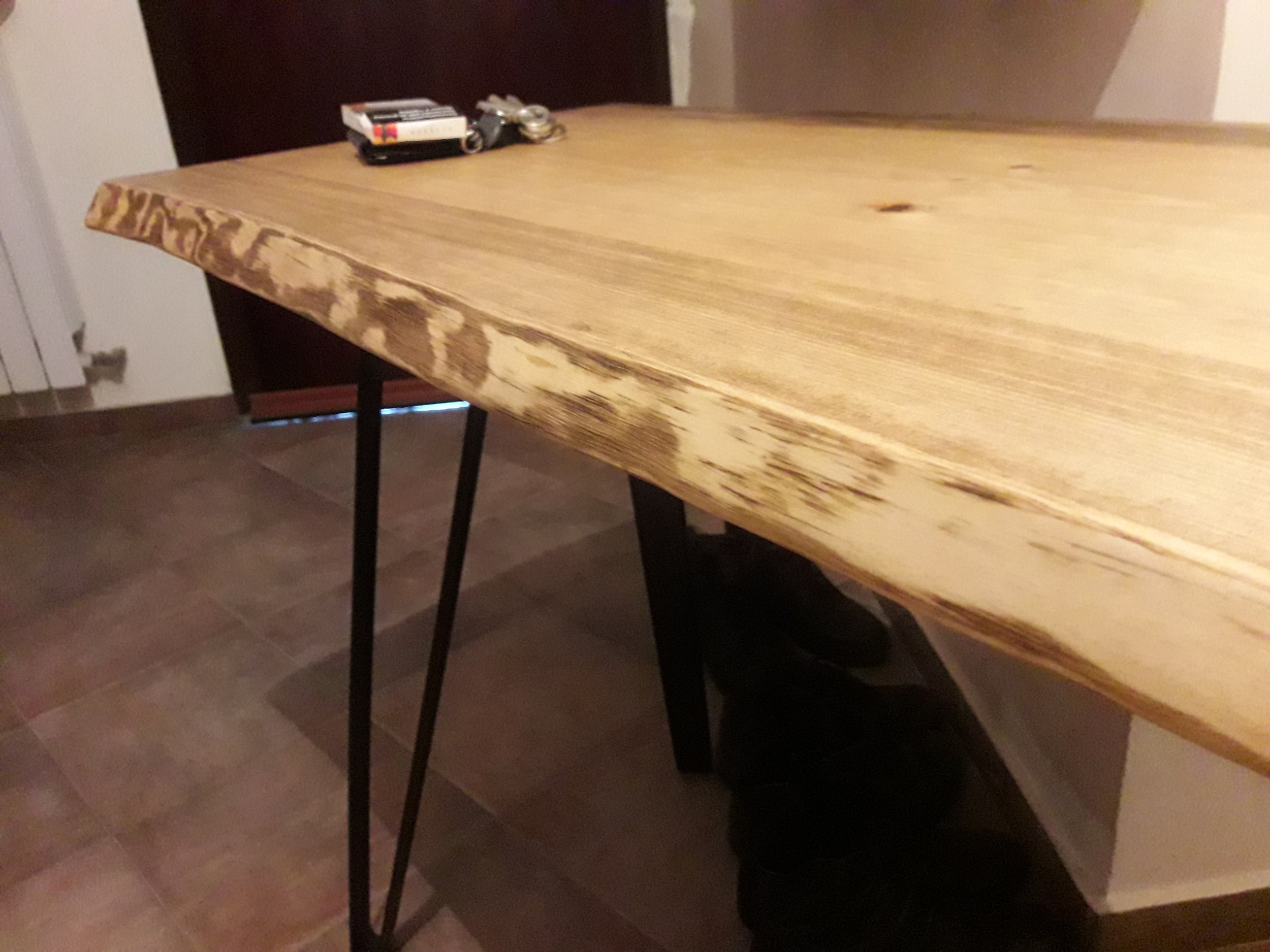 Wooden table with metal legs in a room, holding a few small items on top