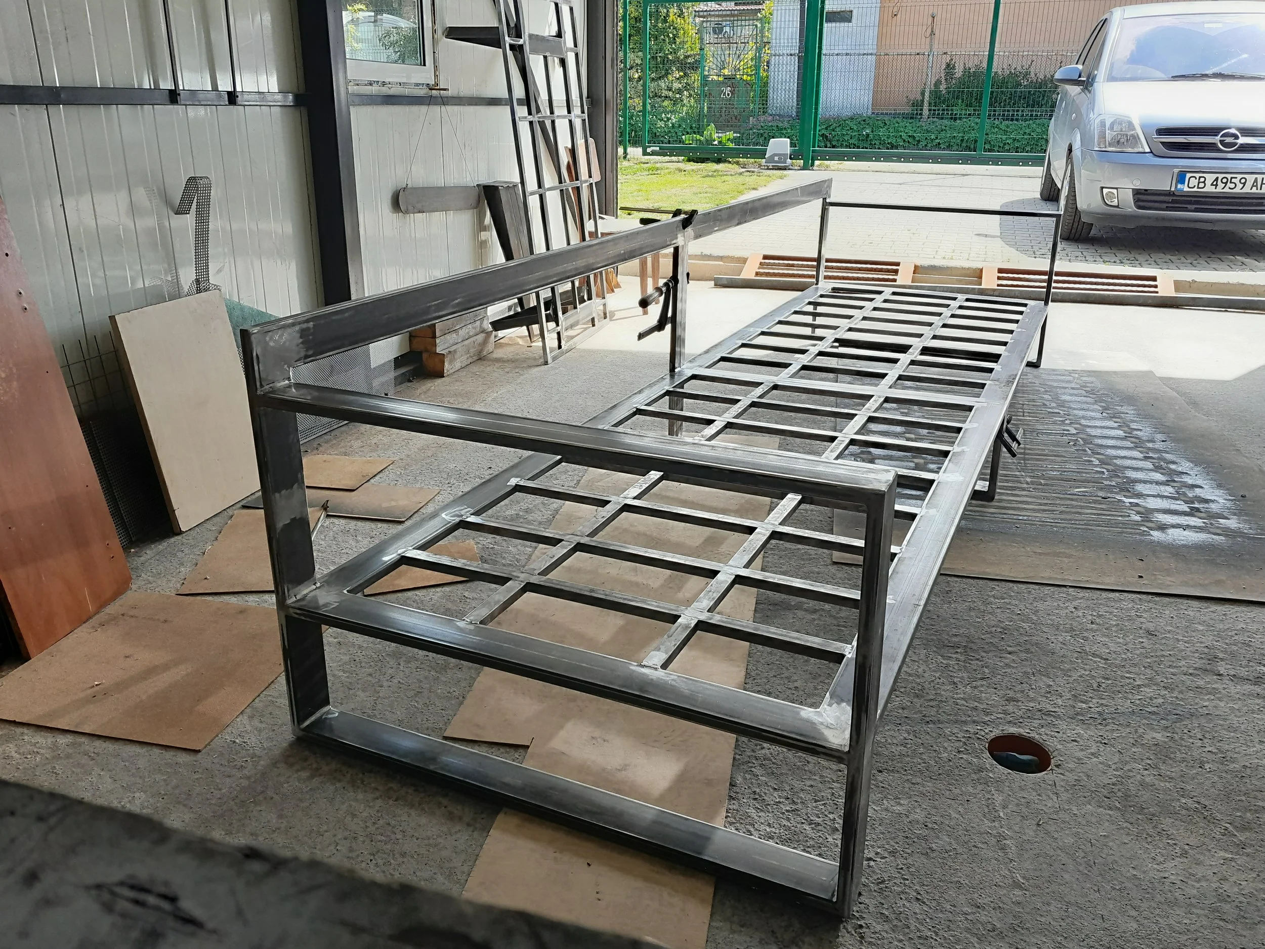 Metal frame structure in a workshop with tools and materials in the background.