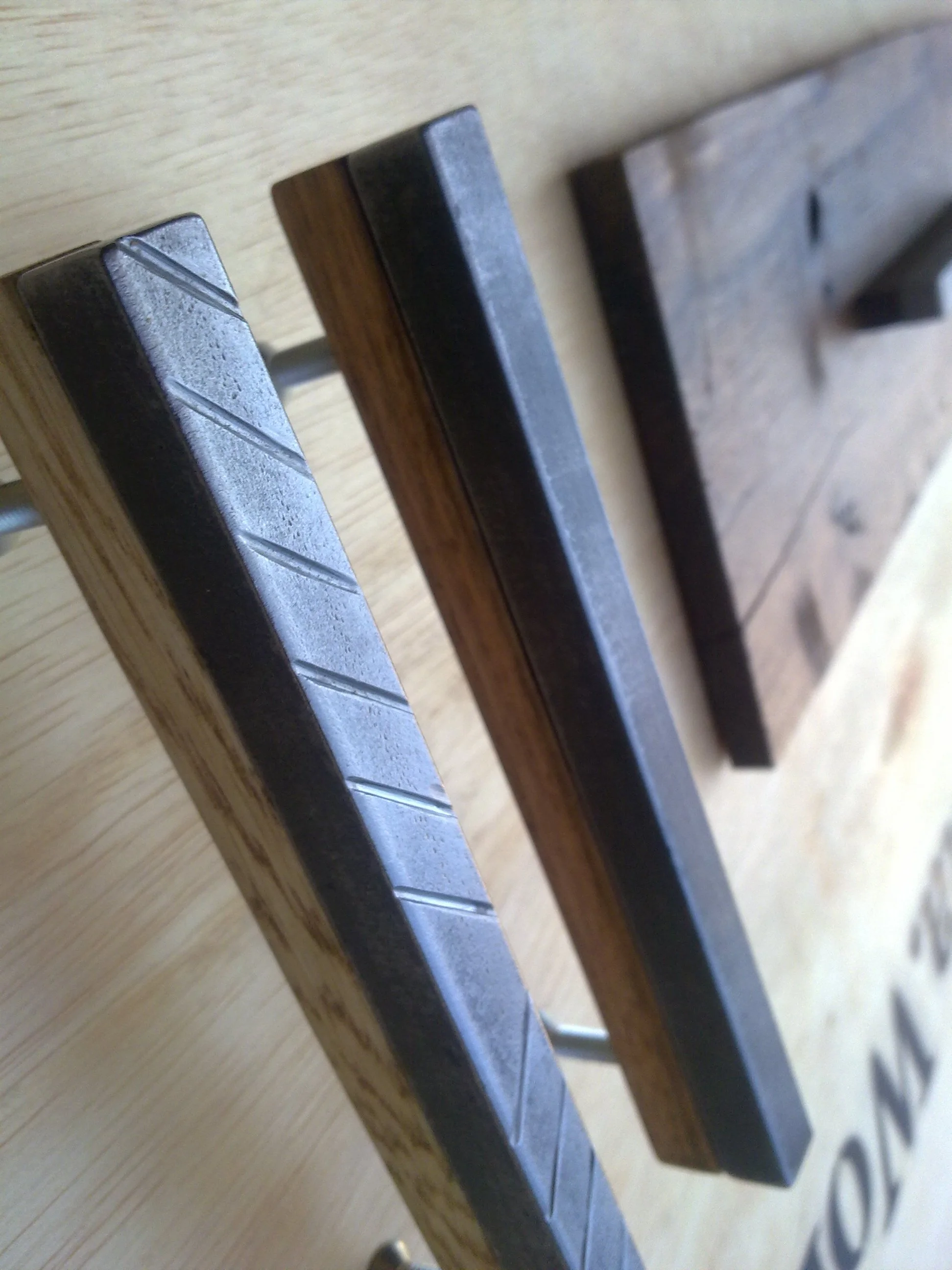 Close-up of metal and wood hooks attached to a background with letters partially visible.