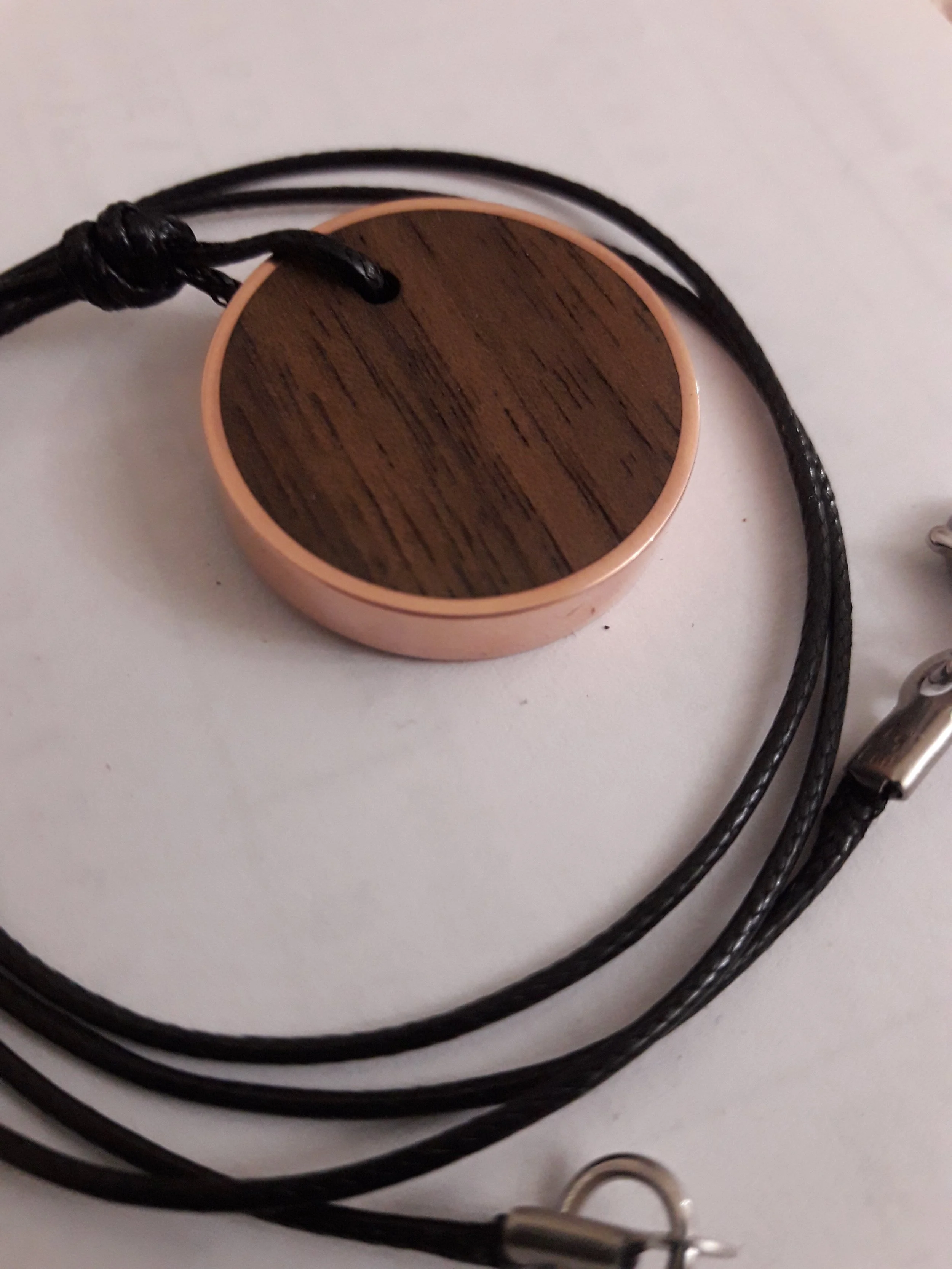 Wooden pendant with leather cord on white background