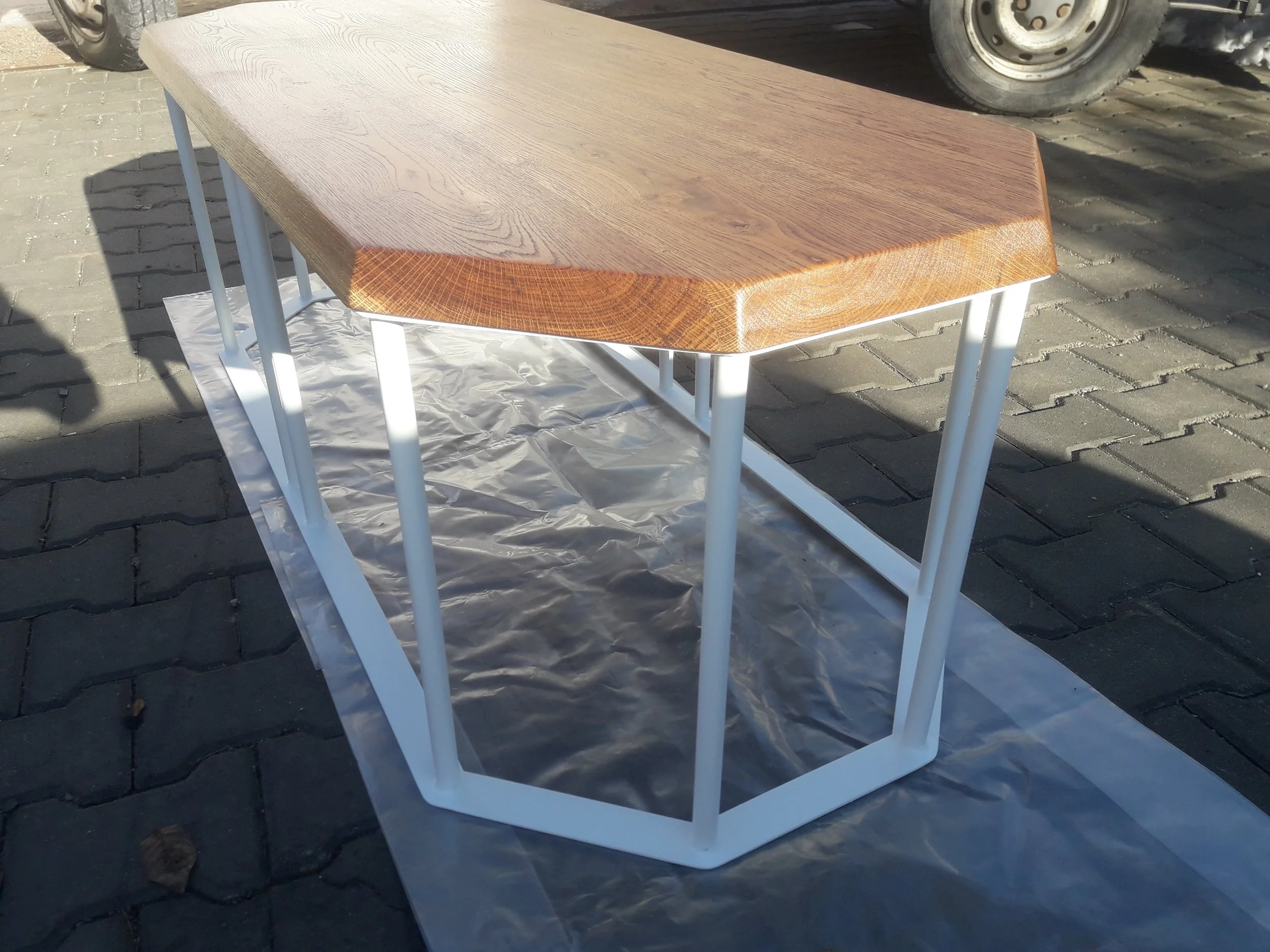 Wooden table with white metal legs on a paved surface