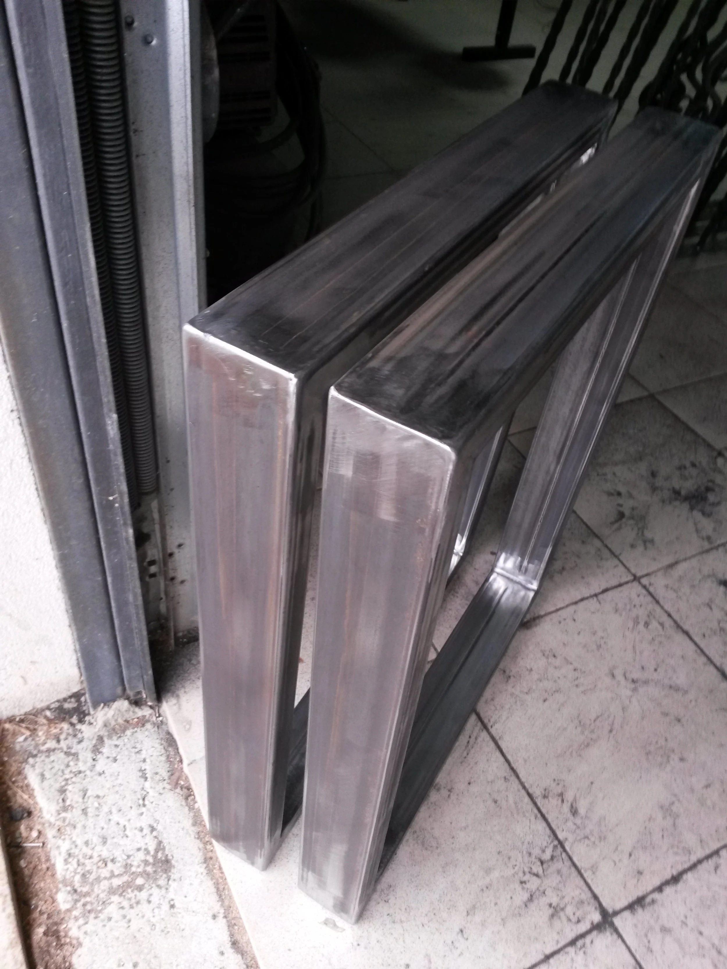 Two large rectangular metal frames on a tiled floor