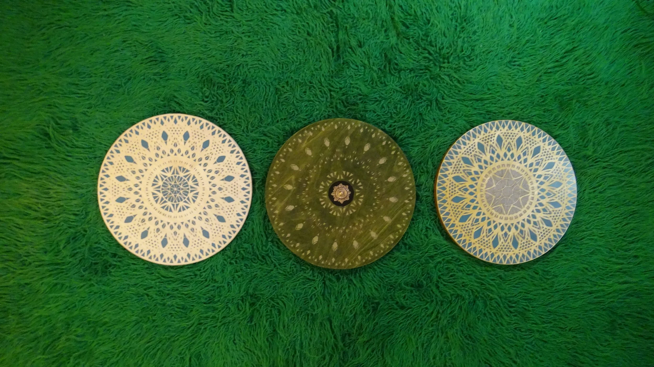 Three intricate circular patterns on a green textured surface.