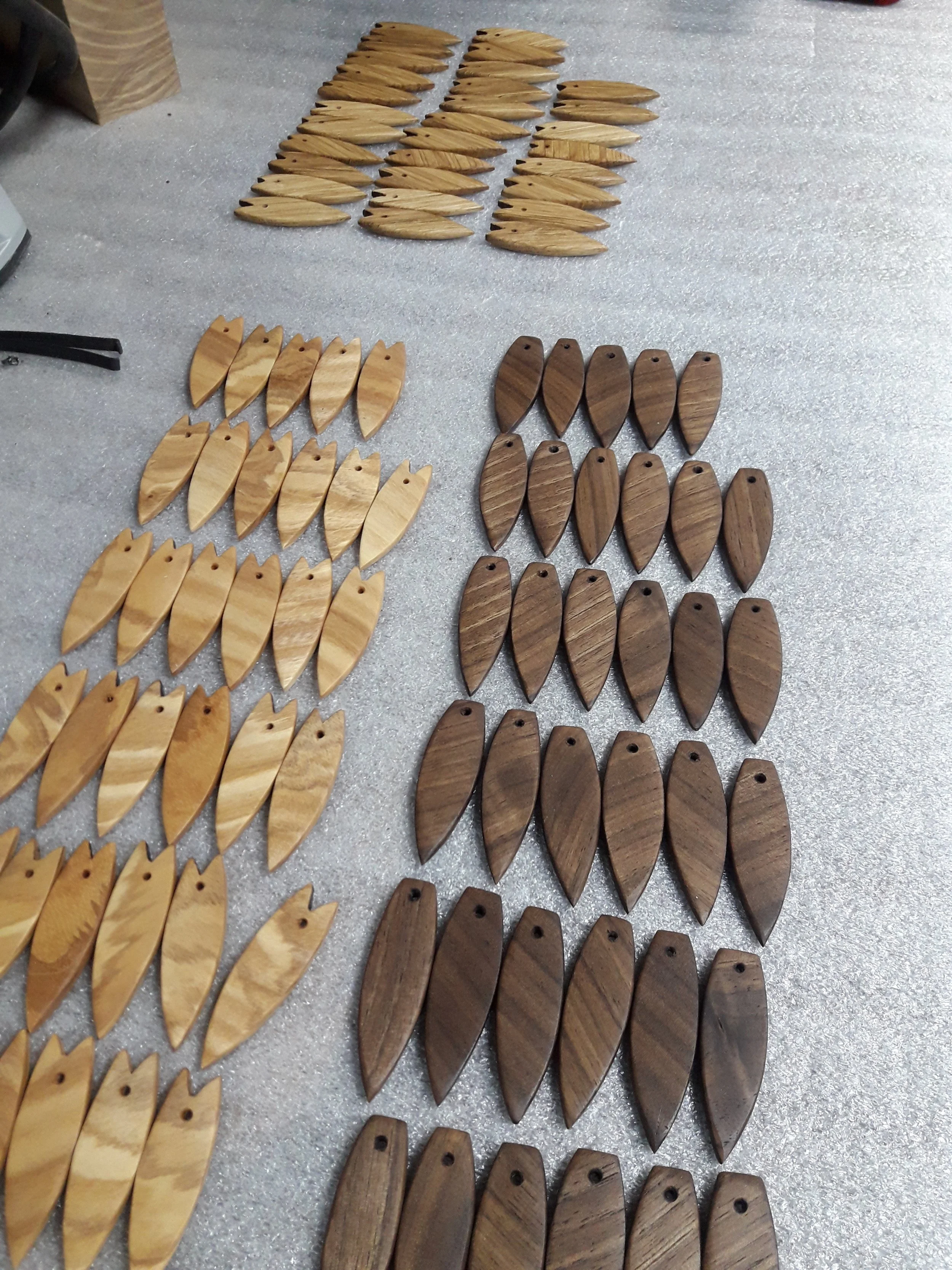 A collection of wooden fish-shaped pendants or keychains in light and dark wood on a table.