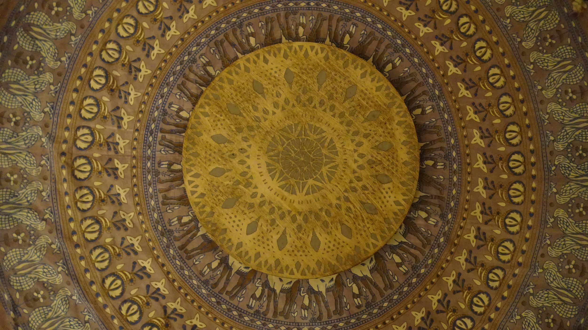 Intricate ceiling design with concentric circular patterns and geometric motifs in brown and gold tones.