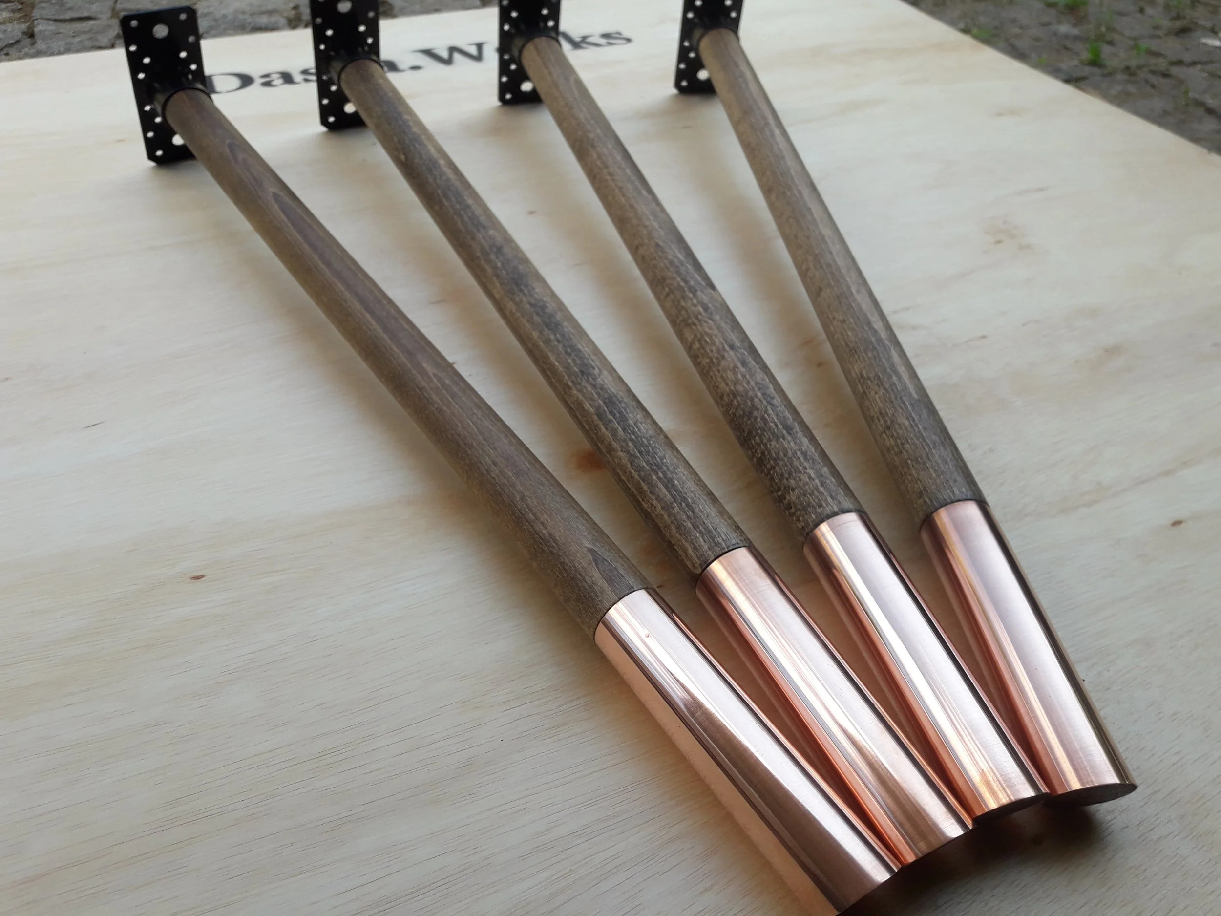 Three wooden legs with metal tips and brackets on a wooden surface