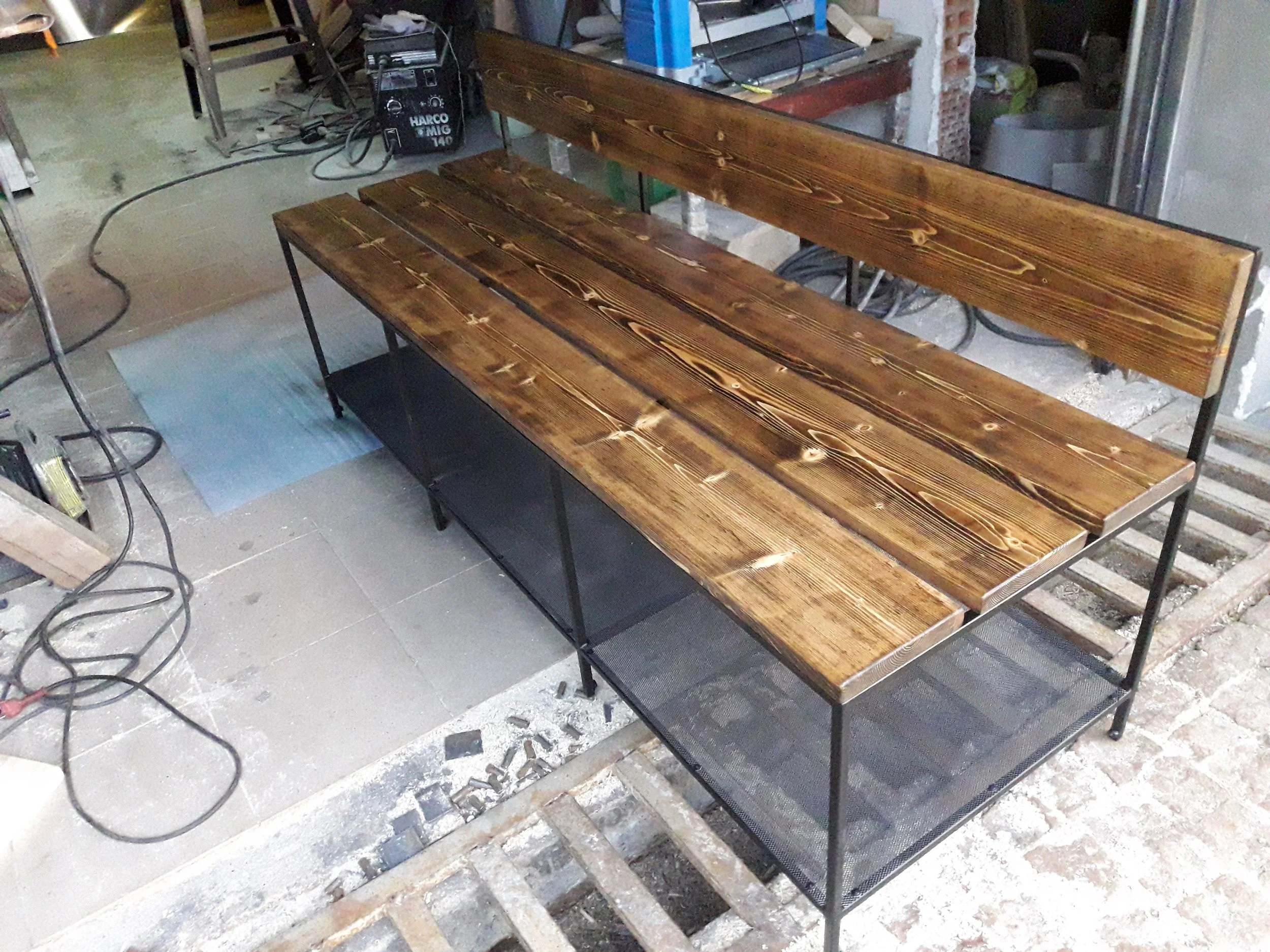 Wooden bench with metal frame and mesh shelf in workshop
