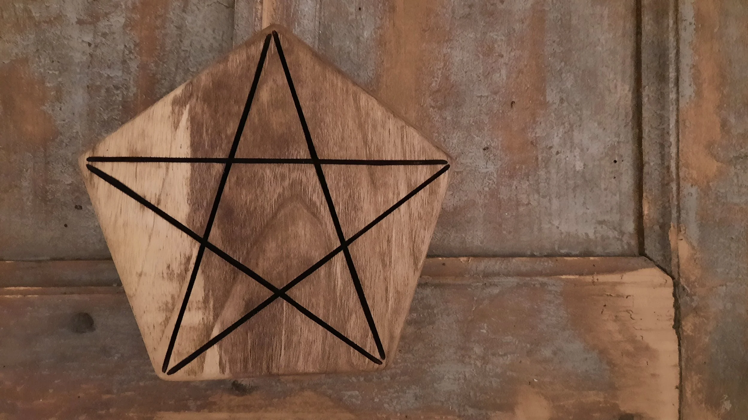 Wooden pentagon with pentagram on a textured wooden background