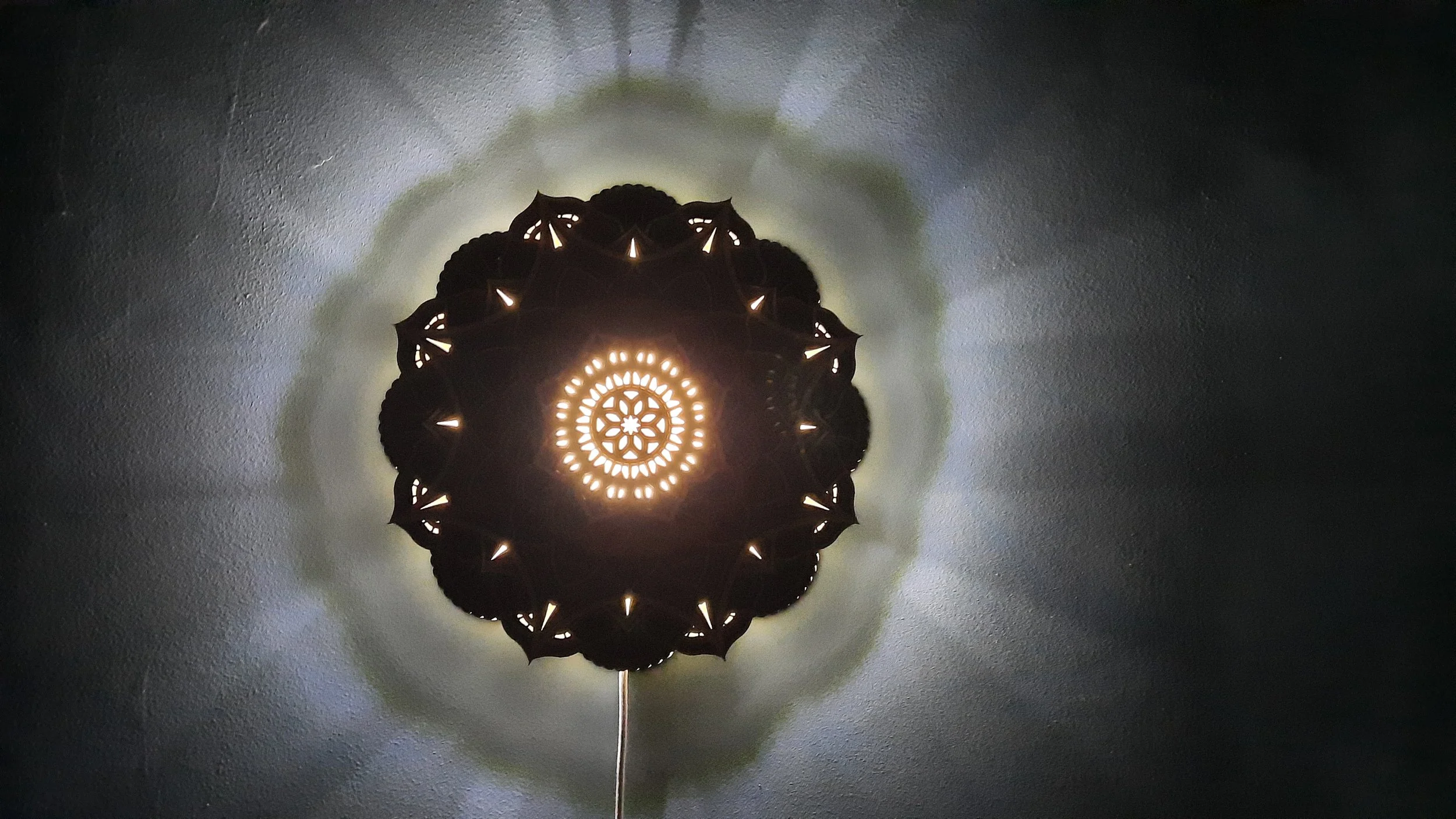 Ornate ceiling light casting intricate patterns on a wall.