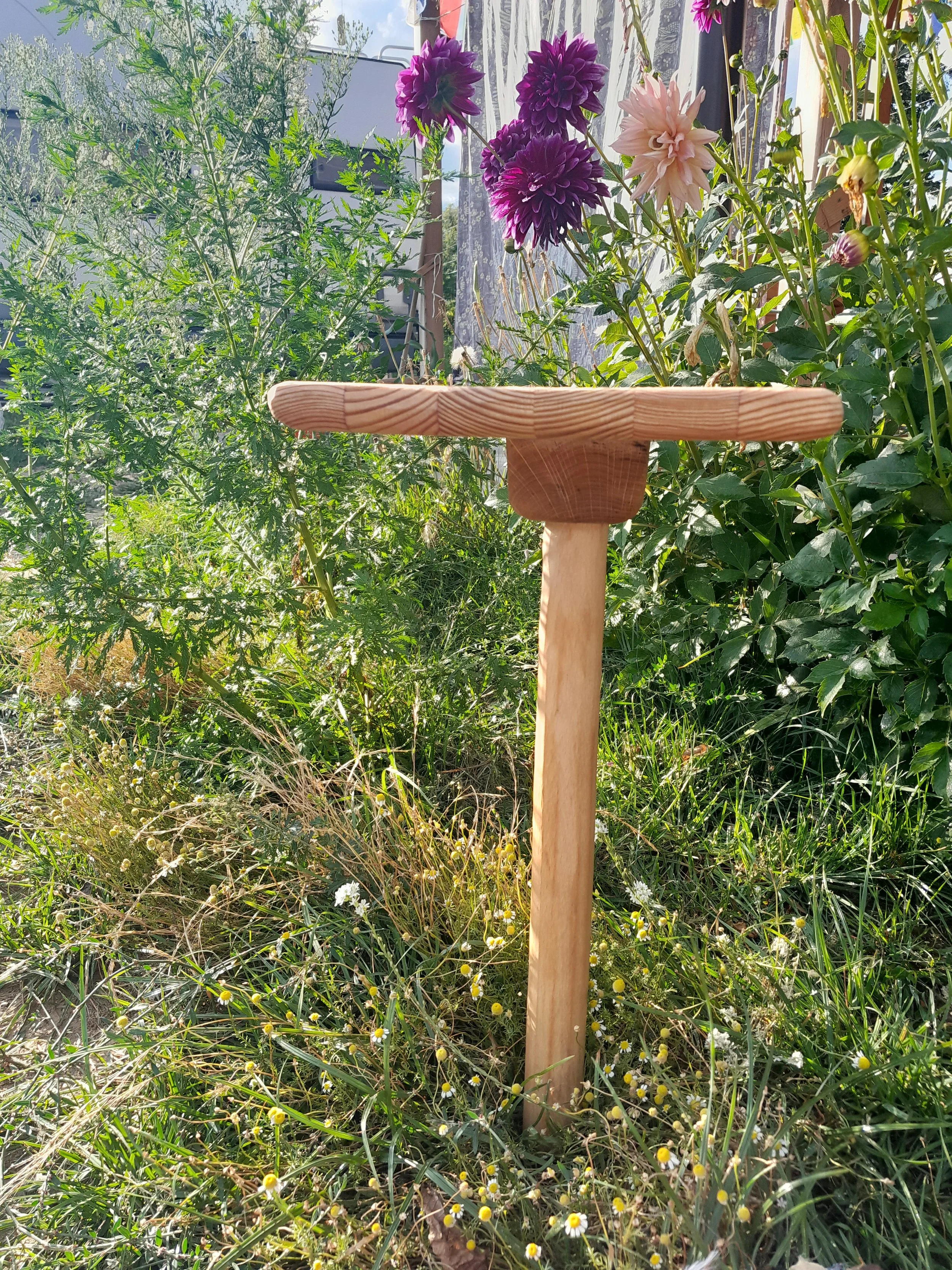 Wooden plant support in a garden with purple dahlias and green foliage