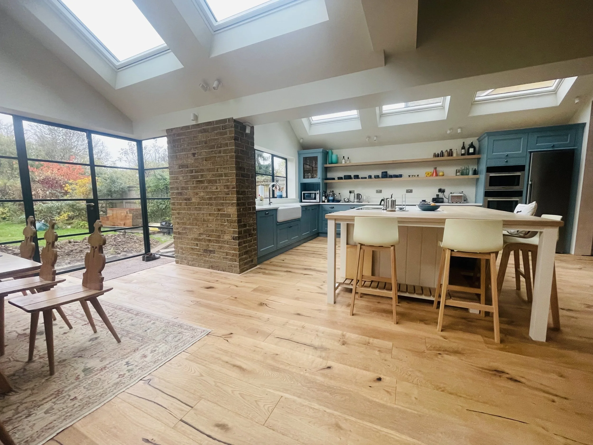 Spacious kitchen with vaulted ceiling, skylights, blue cabinets, open shelves, and a large white island with bar stools.