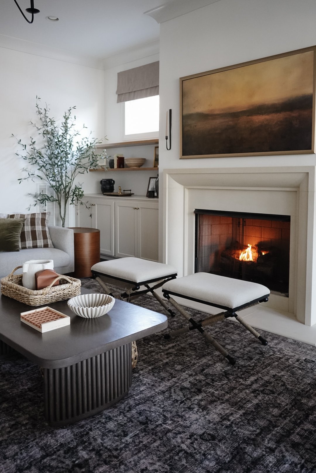Cozy living room with a fireplace, neutral-toned chairs, and abstract wall art