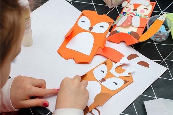 Young child works on an arts and crafts project making a cut-paper fox