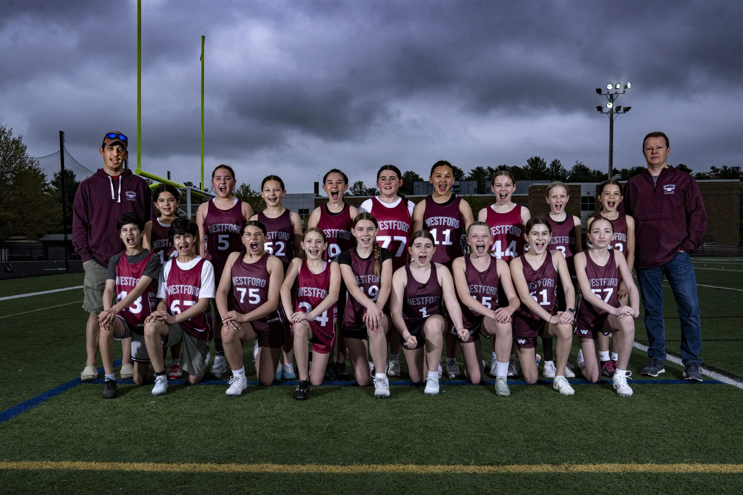 Westford girls lacrosse team photo on field in Massachusetts with dramatic cloudy sky by Fuel Media House