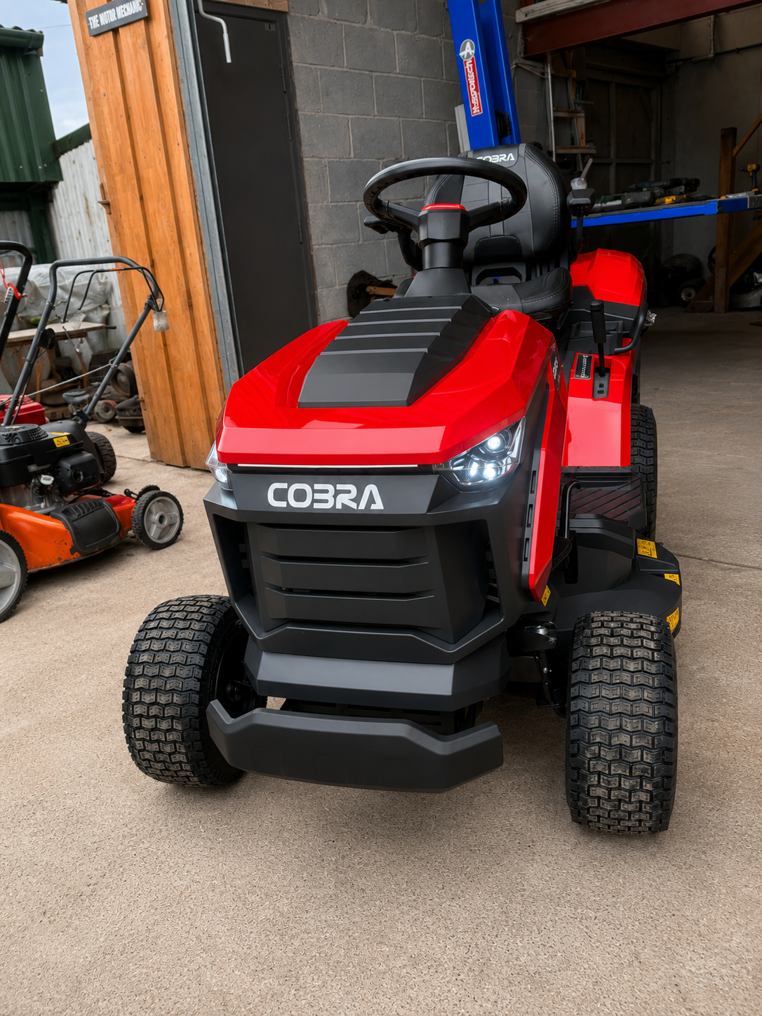 Red and black ride-on toy vehicle with the brand name "COBRA" on front, parked indoors in a garage or workshop.