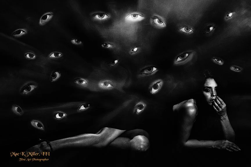 The artwork is a fine art surreal black and white composition featuring a reclining figure with many eyes watching.