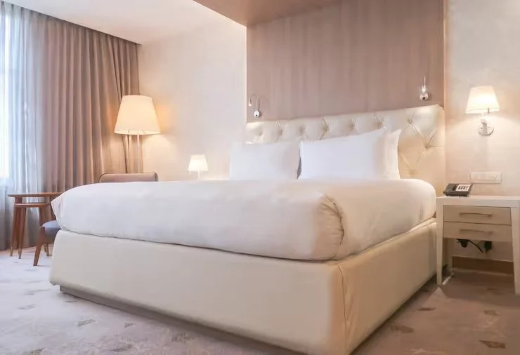 Modern hotel room with a large bed, bedside lamps, and curtains.