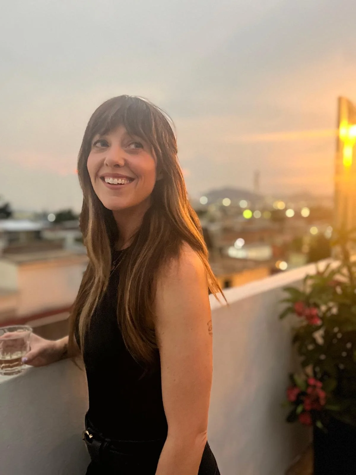 A young woman with long, wavy brown hair and blue eyes sitting inside a car, wearing a purple bandana, black leather jacket, and a gray seatbelt.
