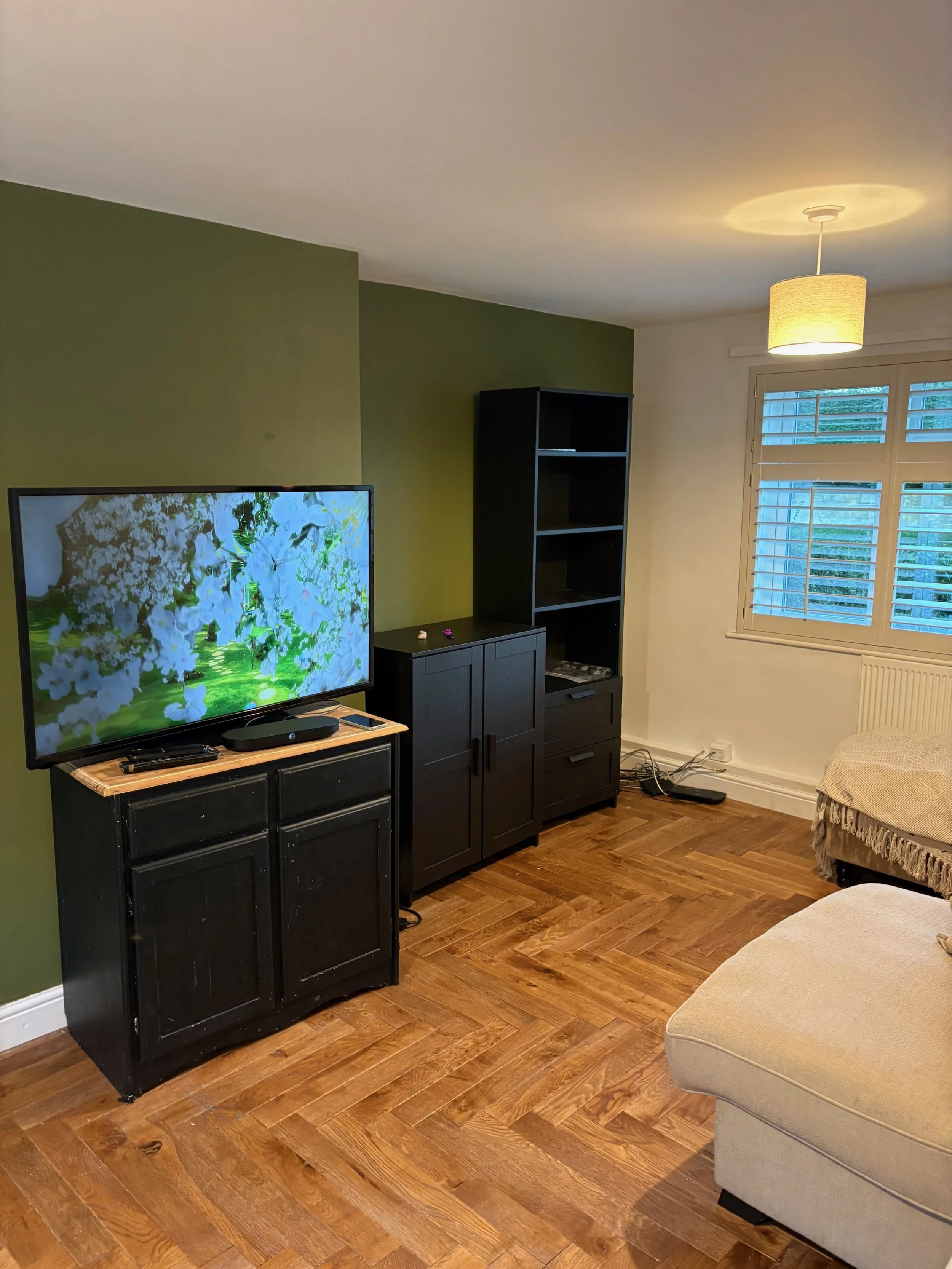 Black and white image of a paint-splattered ladder in front of a partially painted wall.
