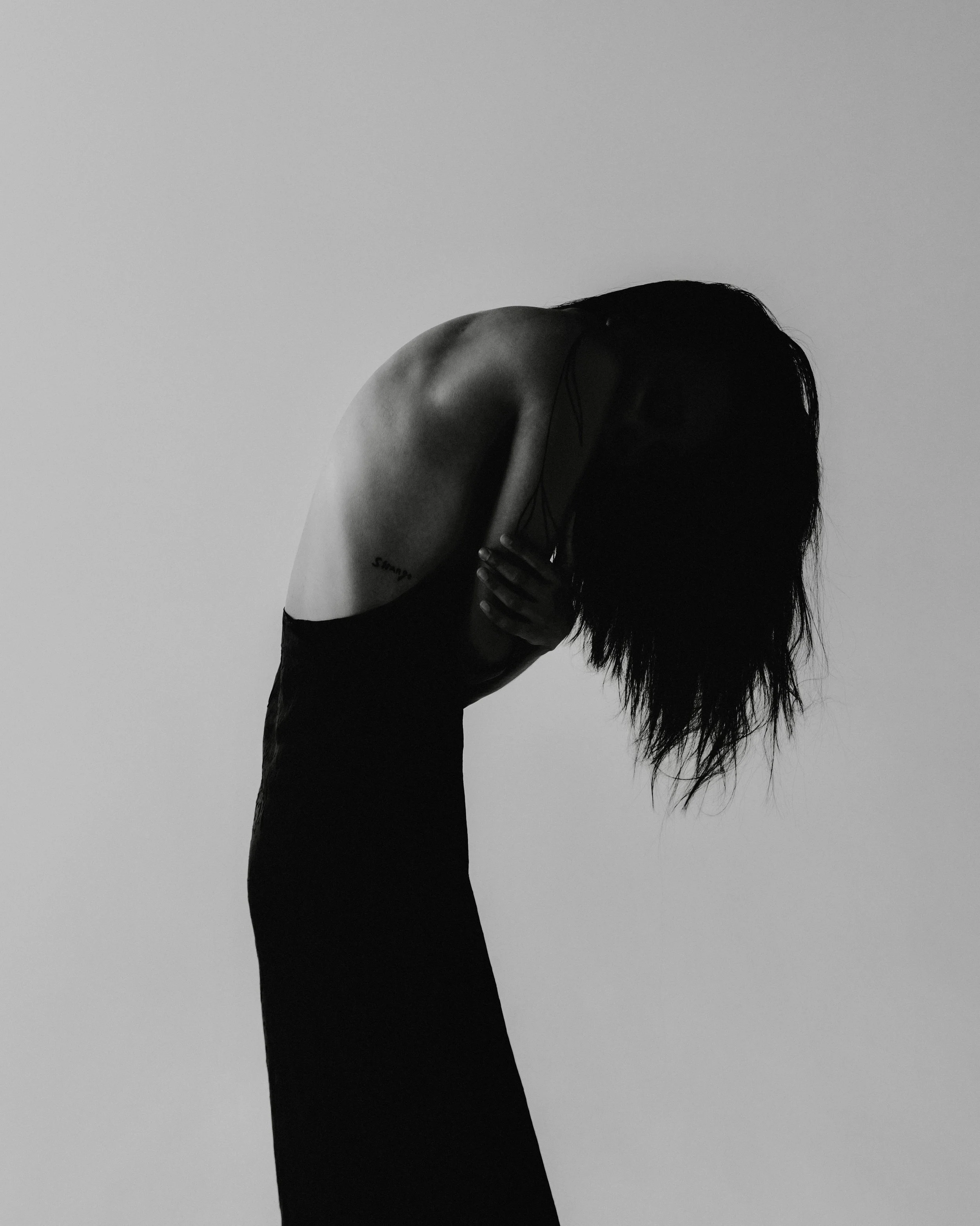 Silhouetted figure bending forward with head lowered, reflecting chronic exhaustion without a crisis and the quiet overwhelm that builds under long-term stress.