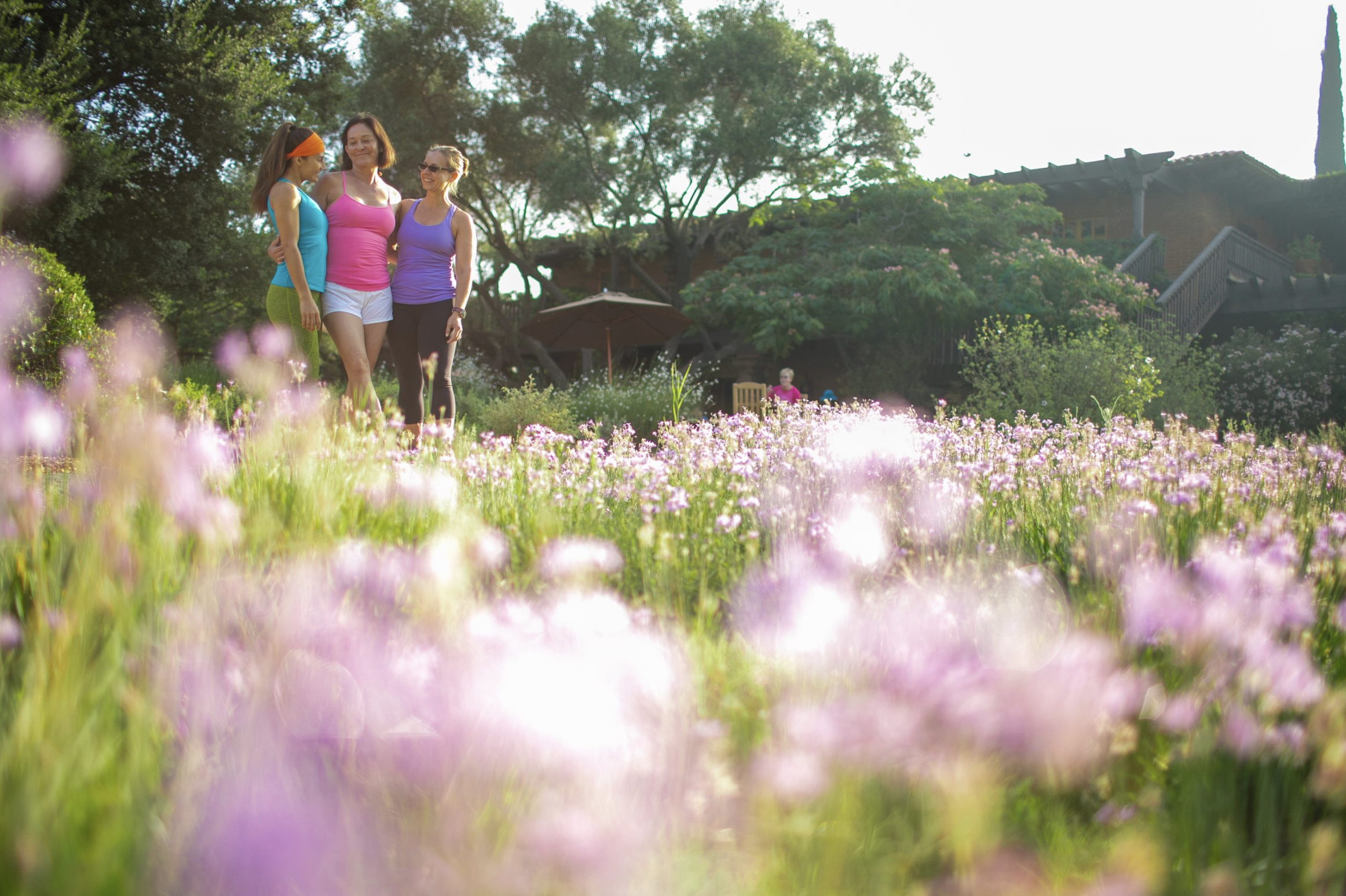 Friends in a blooming field of purple flowers — capturing her coaching philosophy of movement, joy, and nature-based wellbeing.