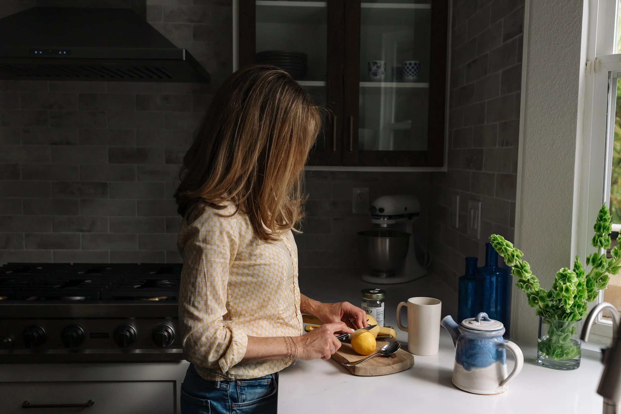 Ilene Schaffer preparing tea in a cozy kitchen — capturing her replenishment philosophy and everyday rituals that support wellbeing and personal growth.