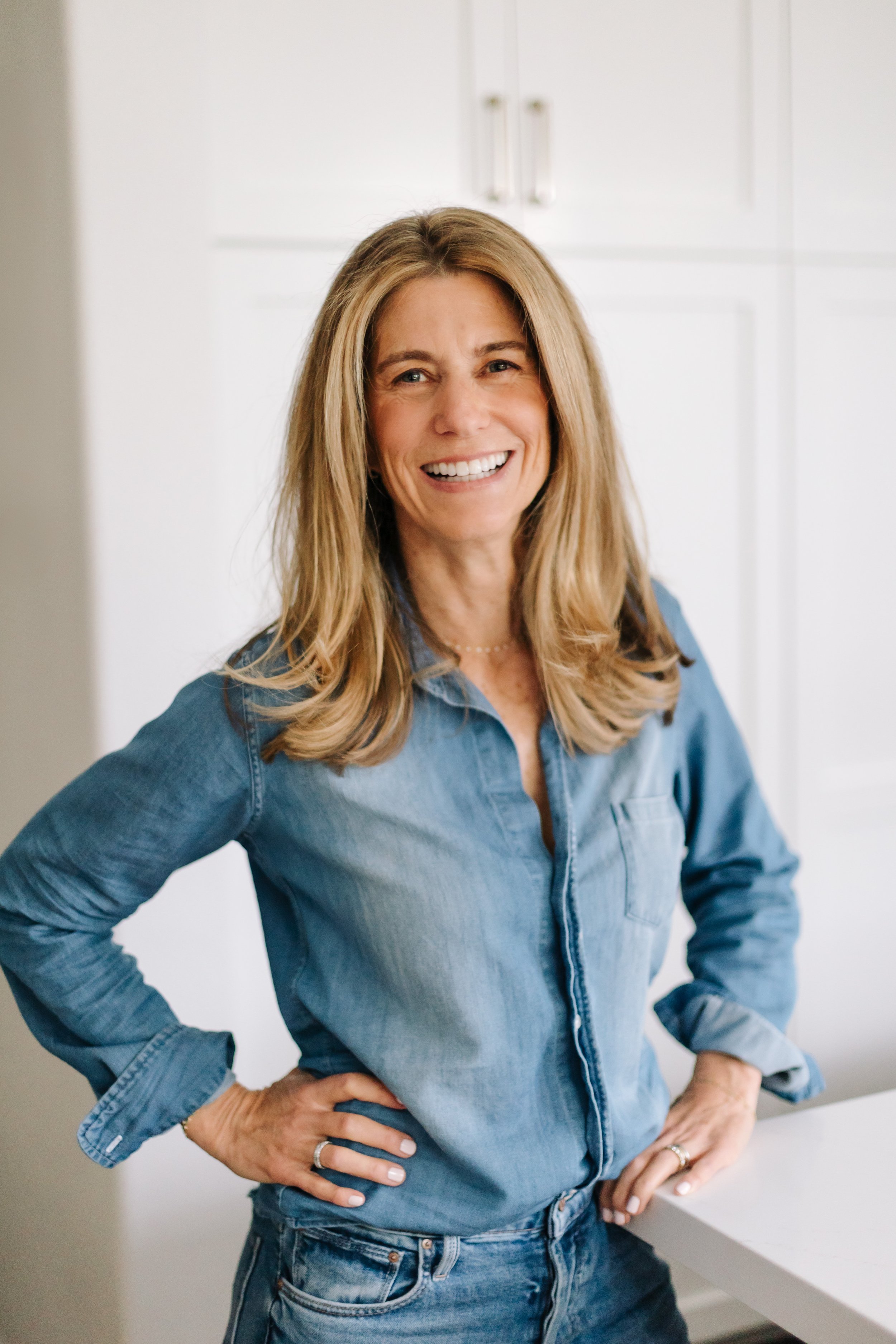 Ilene Schaffer smiling in a bright, modern space — reflecting her approachable, grounded presence as a coach and speaker focused on clarity, wellbeing, and personal connection.