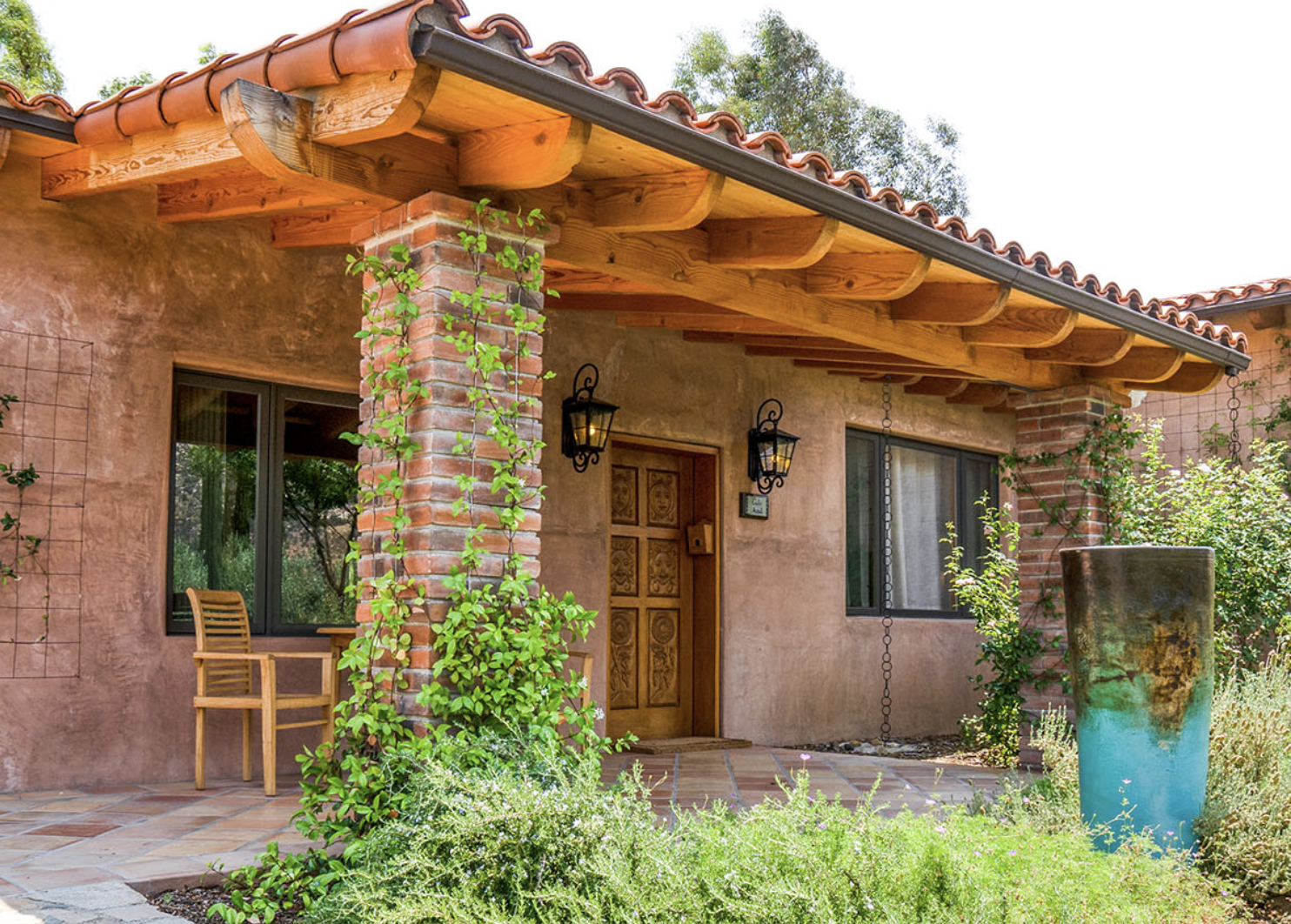 Entrance to a rustic home with carved wooden door and climbing greenery — representing Ilene Schaffer’s warm, grounded approach to coaching and intentional living.