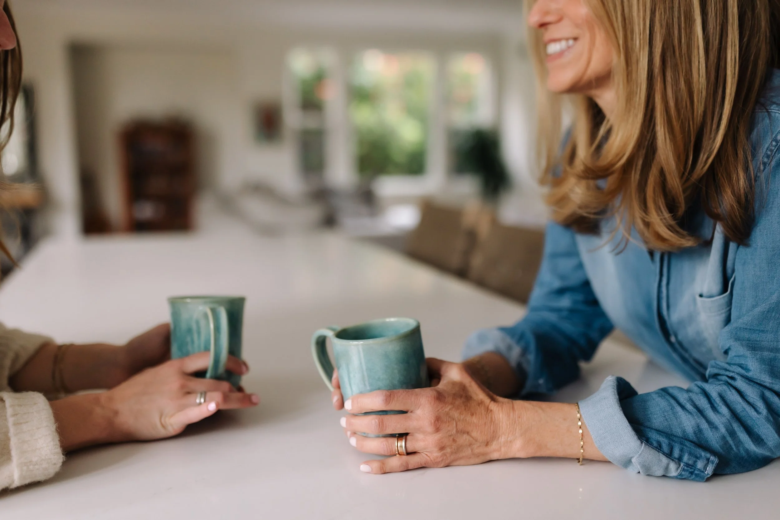 Two people sharing coffee at a sunlit table, creating a warm, relaxed moment.