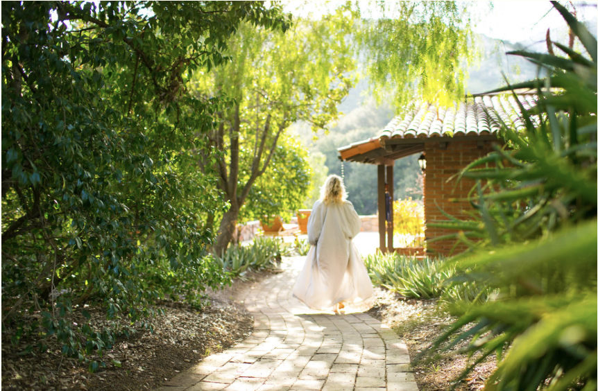 Woman walking barefoot along a sunlit garden path — embodying Ilene Schaffer's coaching philosophy of presence, renewal, and intentional movement through life’s transitions.