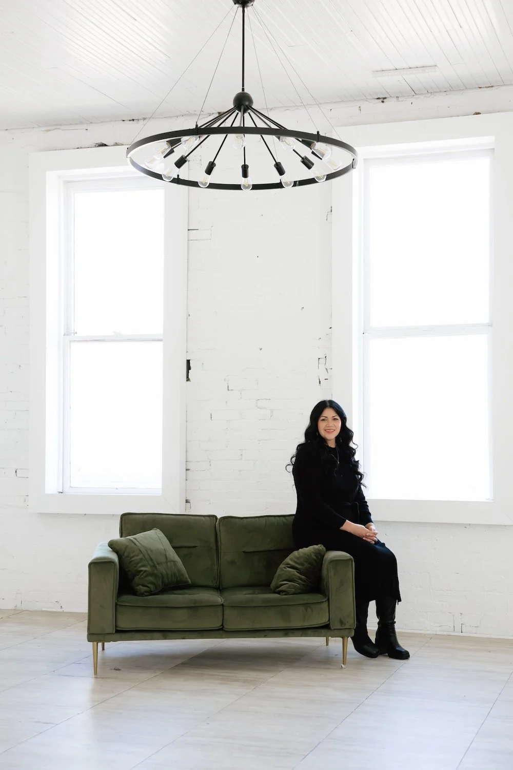 Gabrielle sitting on the edge of the arm of a couch, smiling.