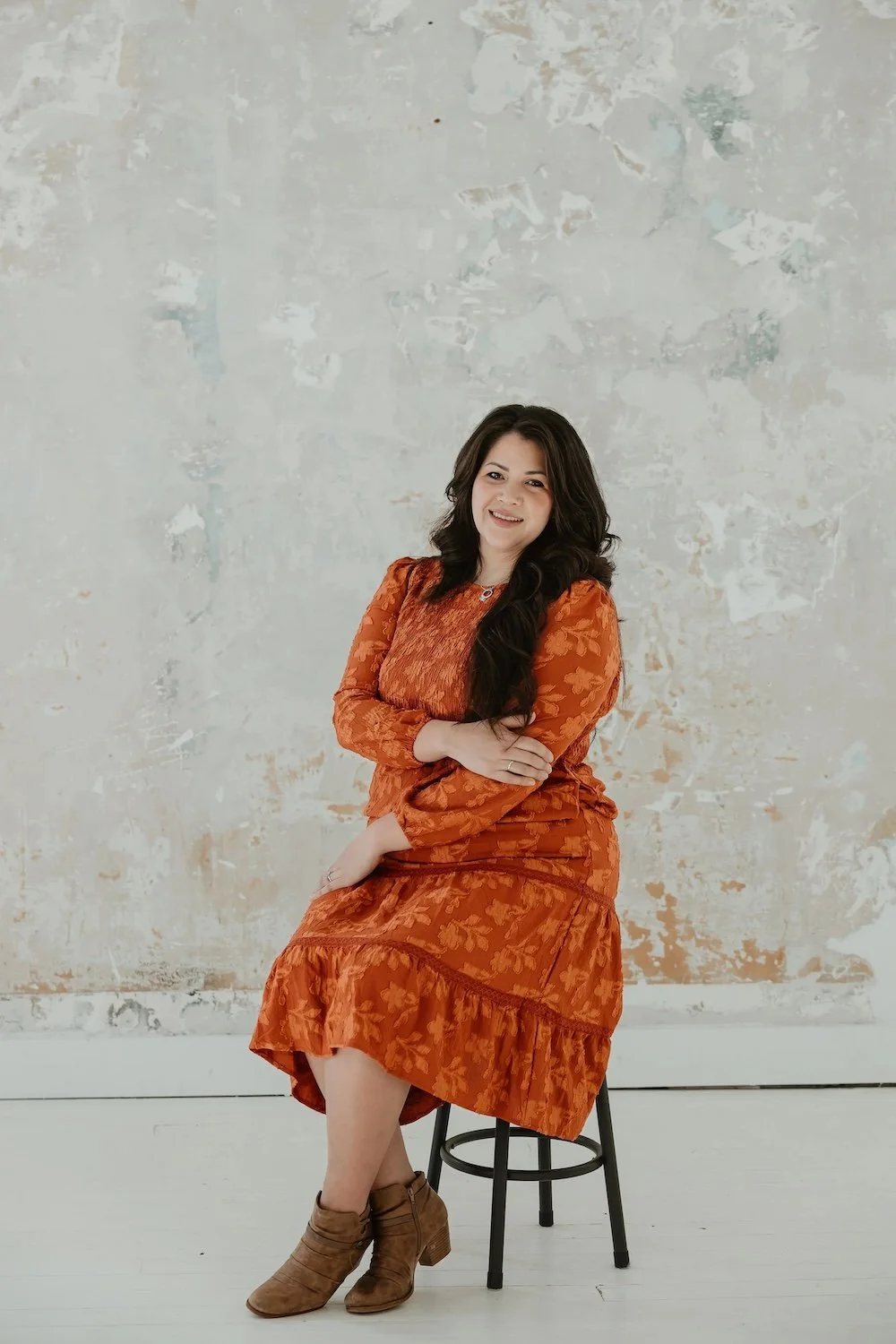 Photo of Gabrielle sitting on a stool, smiling and facing the frame.